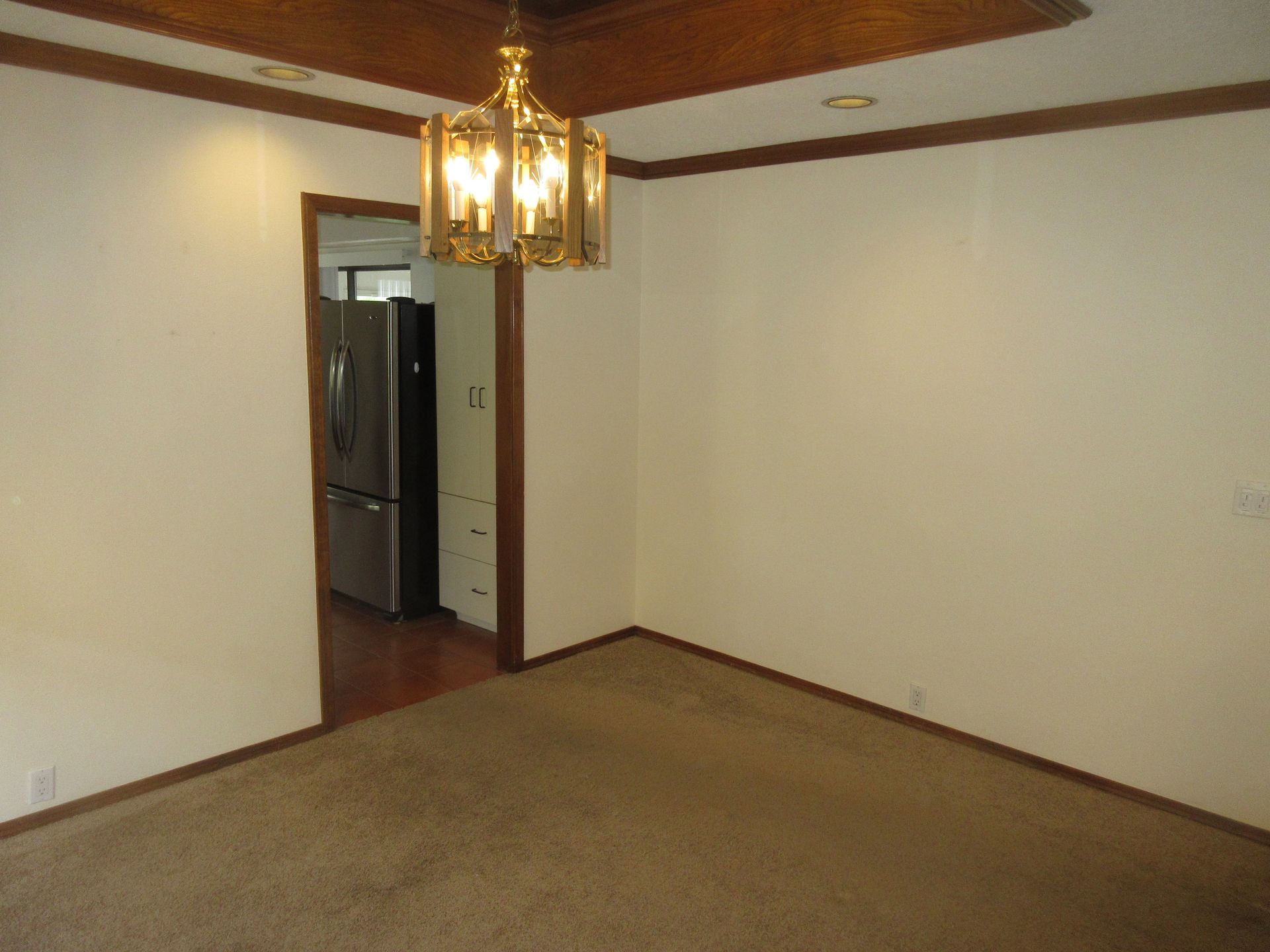 An empty dining room with a chandelier hanging from the ceiling