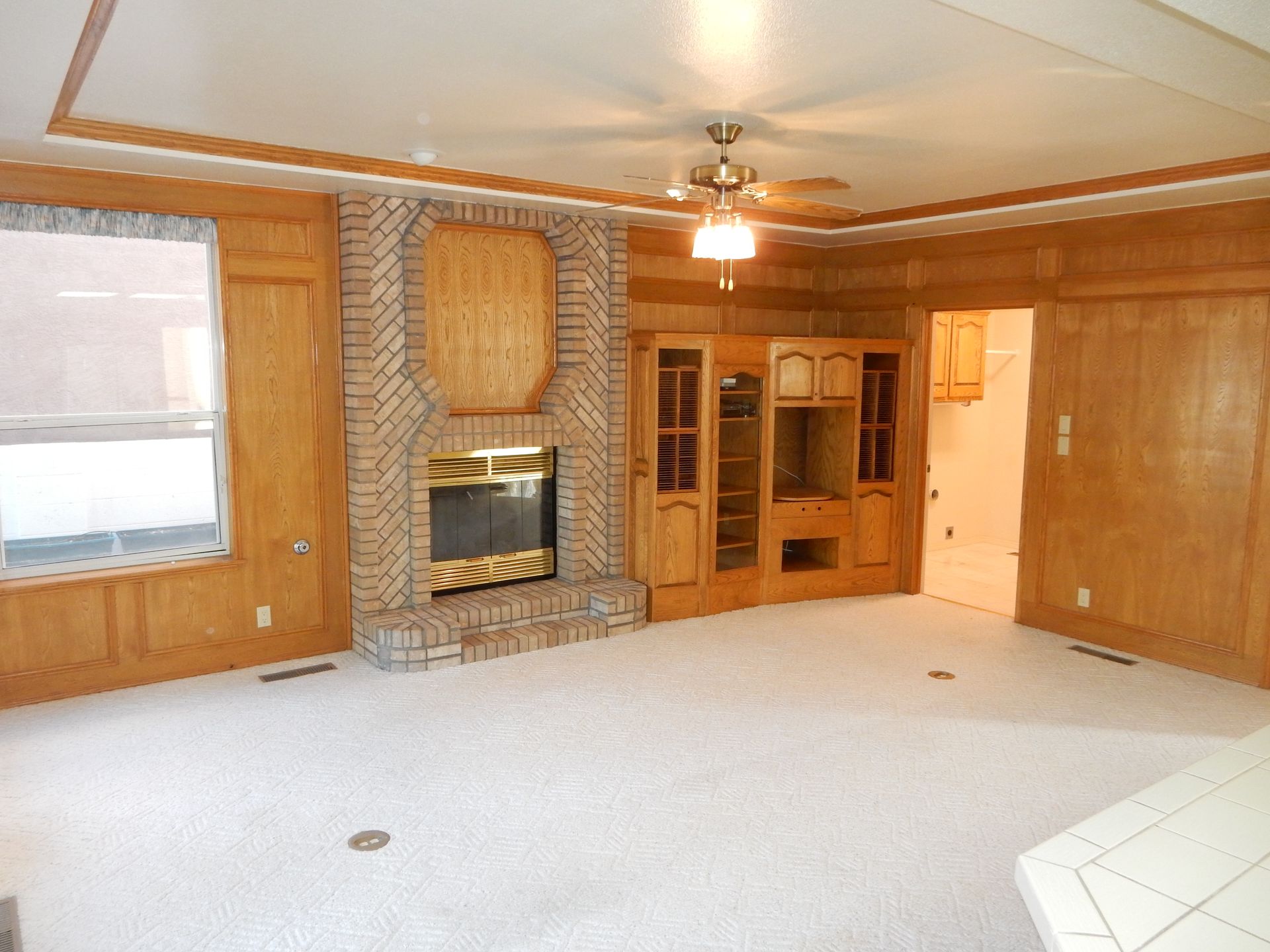 A living room with a fireplace and a ceiling fan