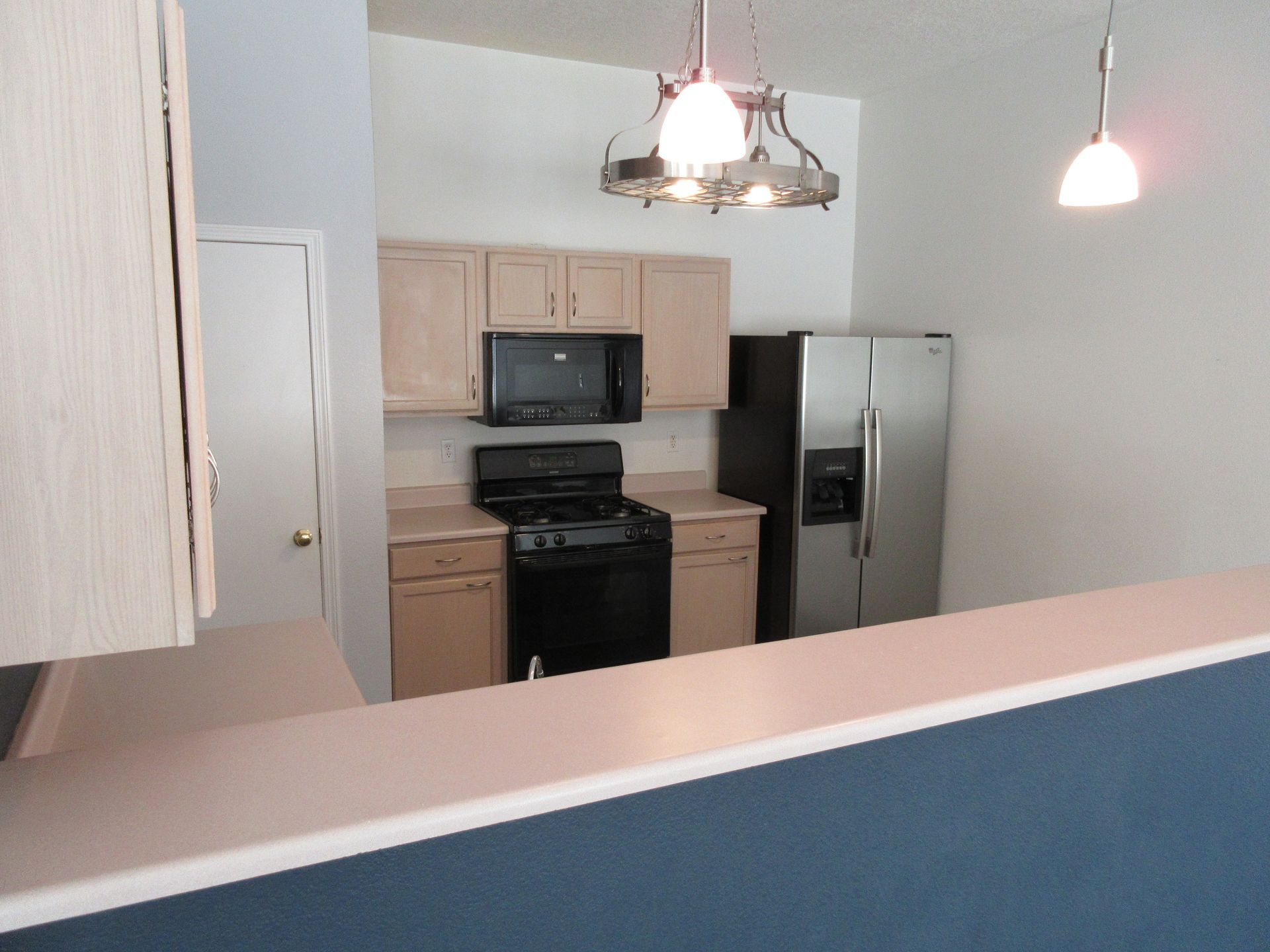 A kitchen with a stove a refrigerator and a microwave