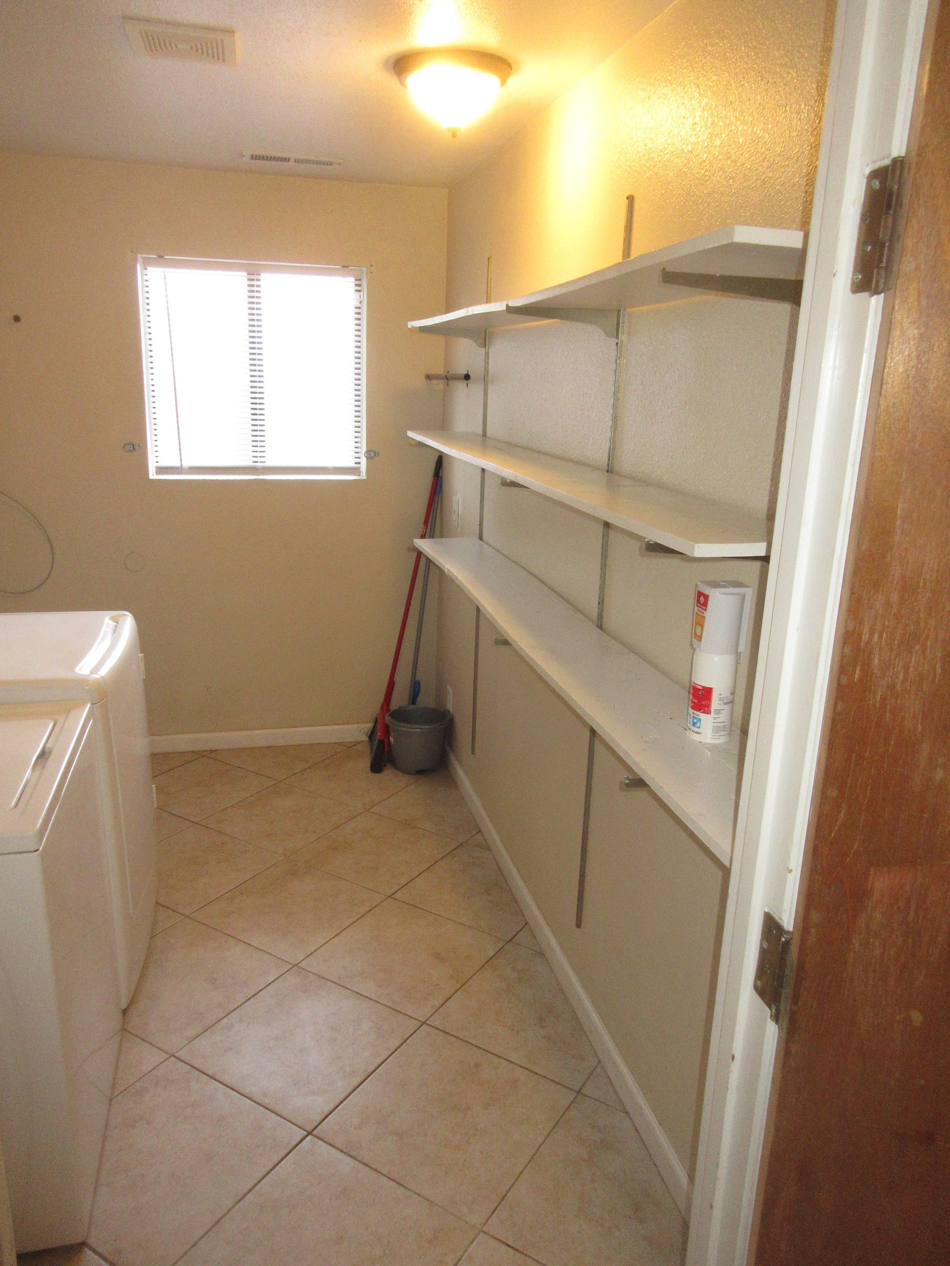 A laundry room with a washer and dryer and shelves