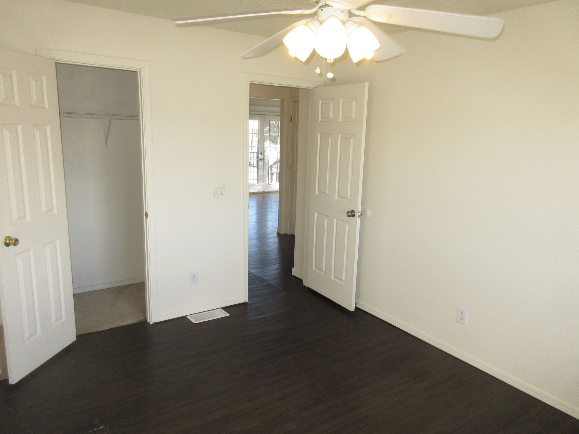 An empty bedroom with a ceiling fan and a closet