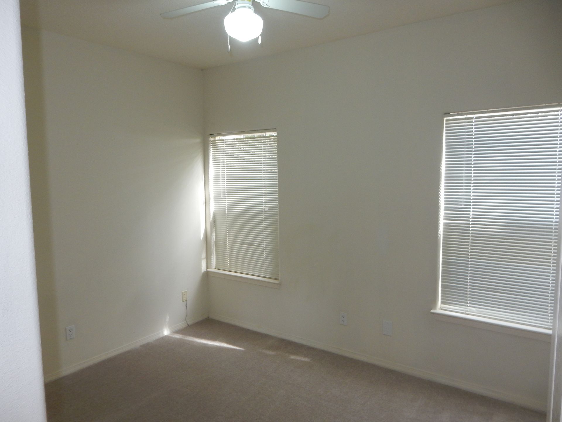 An empty room with blinds and a ceiling fan