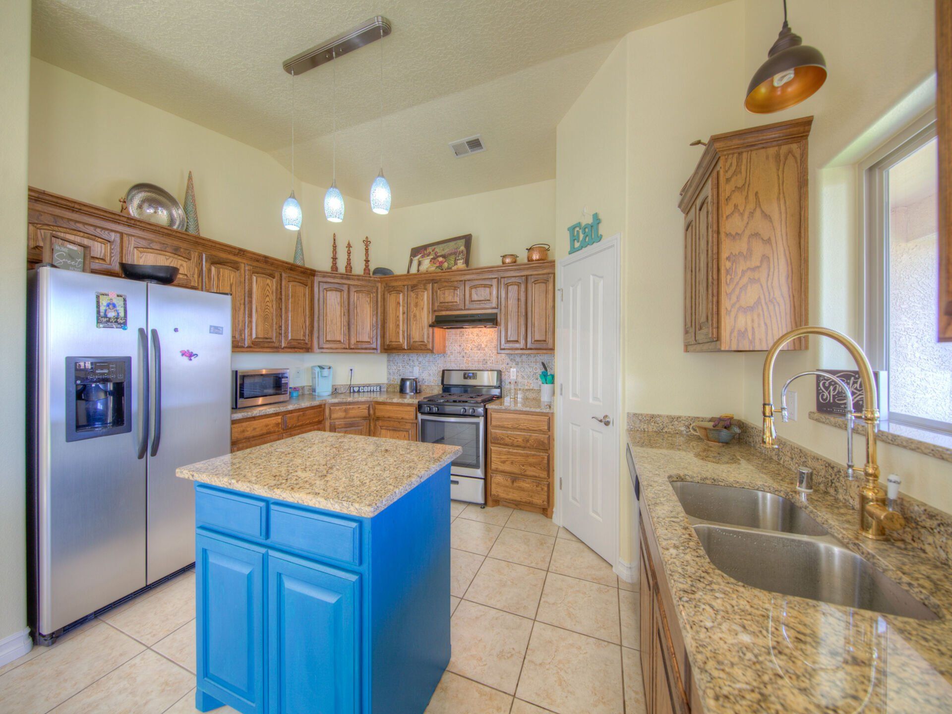 A kitchen with a blue island and a stainless steel refrigerator