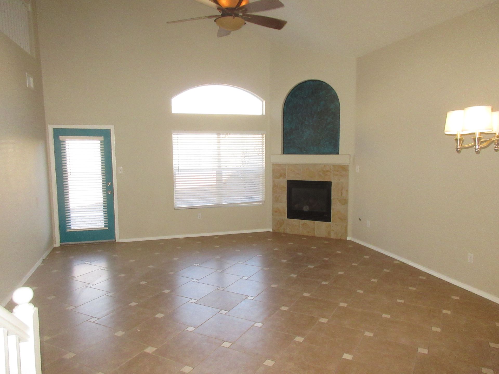 An empty living room with a fireplace and ceiling fan