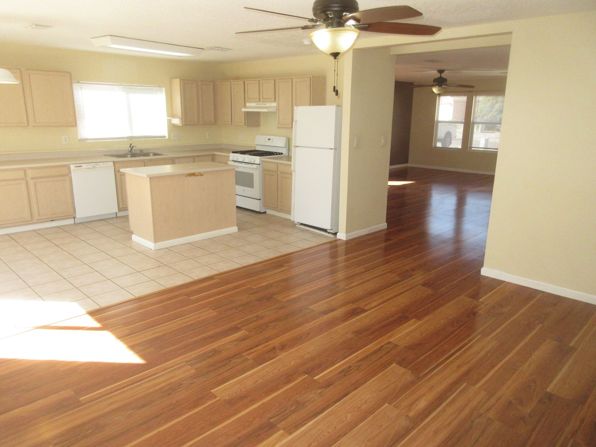 An empty kitchen with hardwood floors and a ceiling fan
