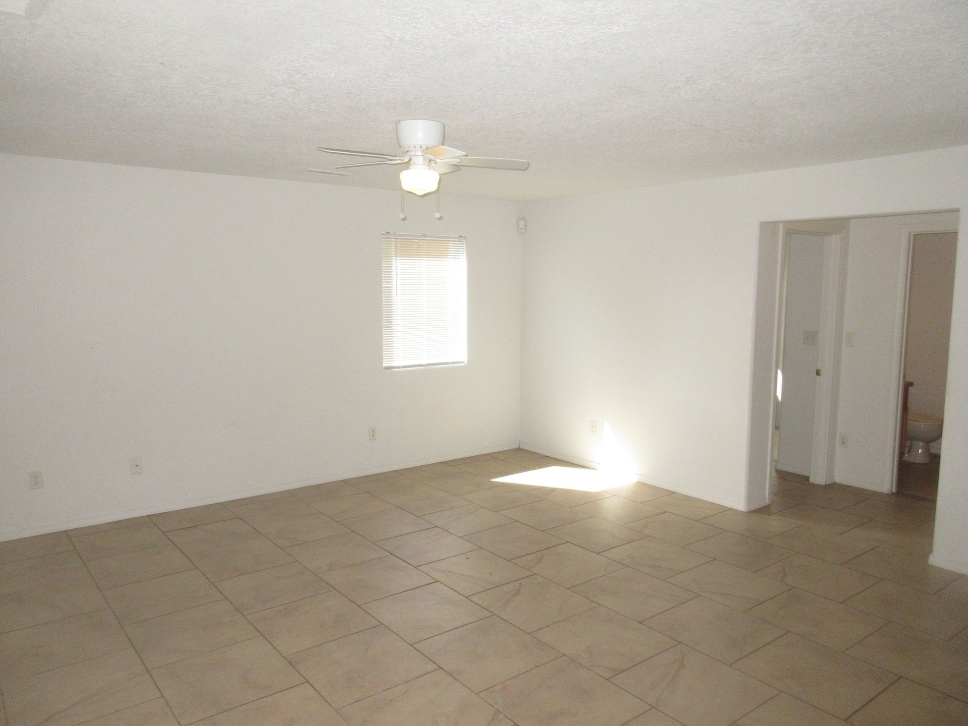 An empty room with a ceiling fan and a window