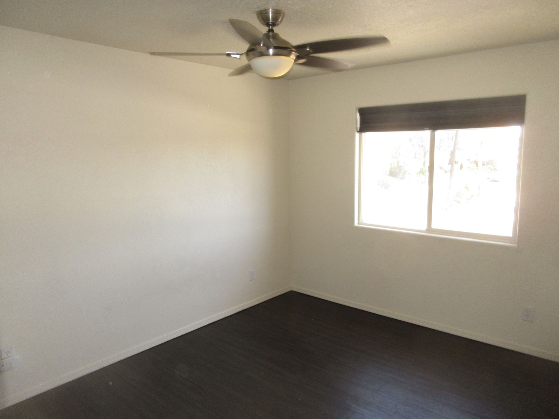 An empty room with a ceiling fan and a window