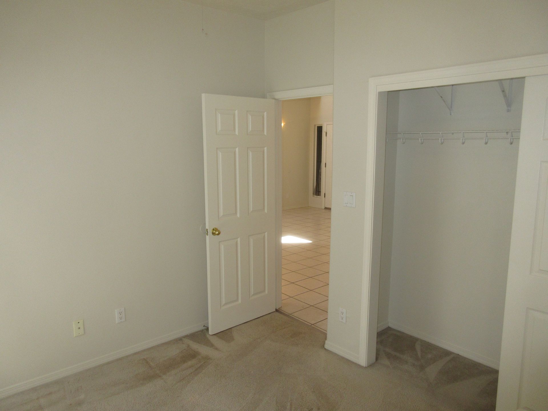 An empty bedroom with a closet and a door leading to a bathroom.