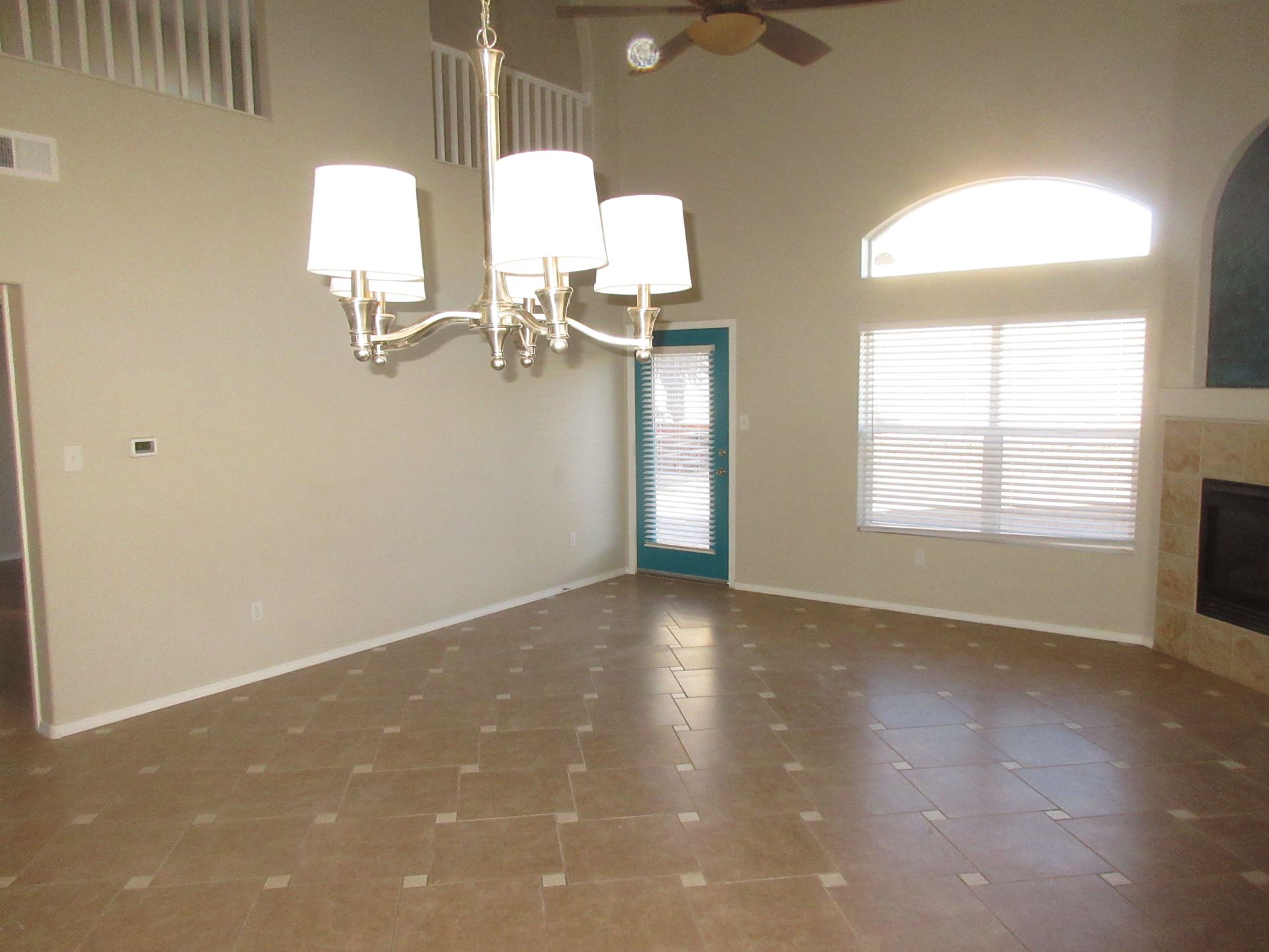 An empty living room with a chandelier and a ceiling fan