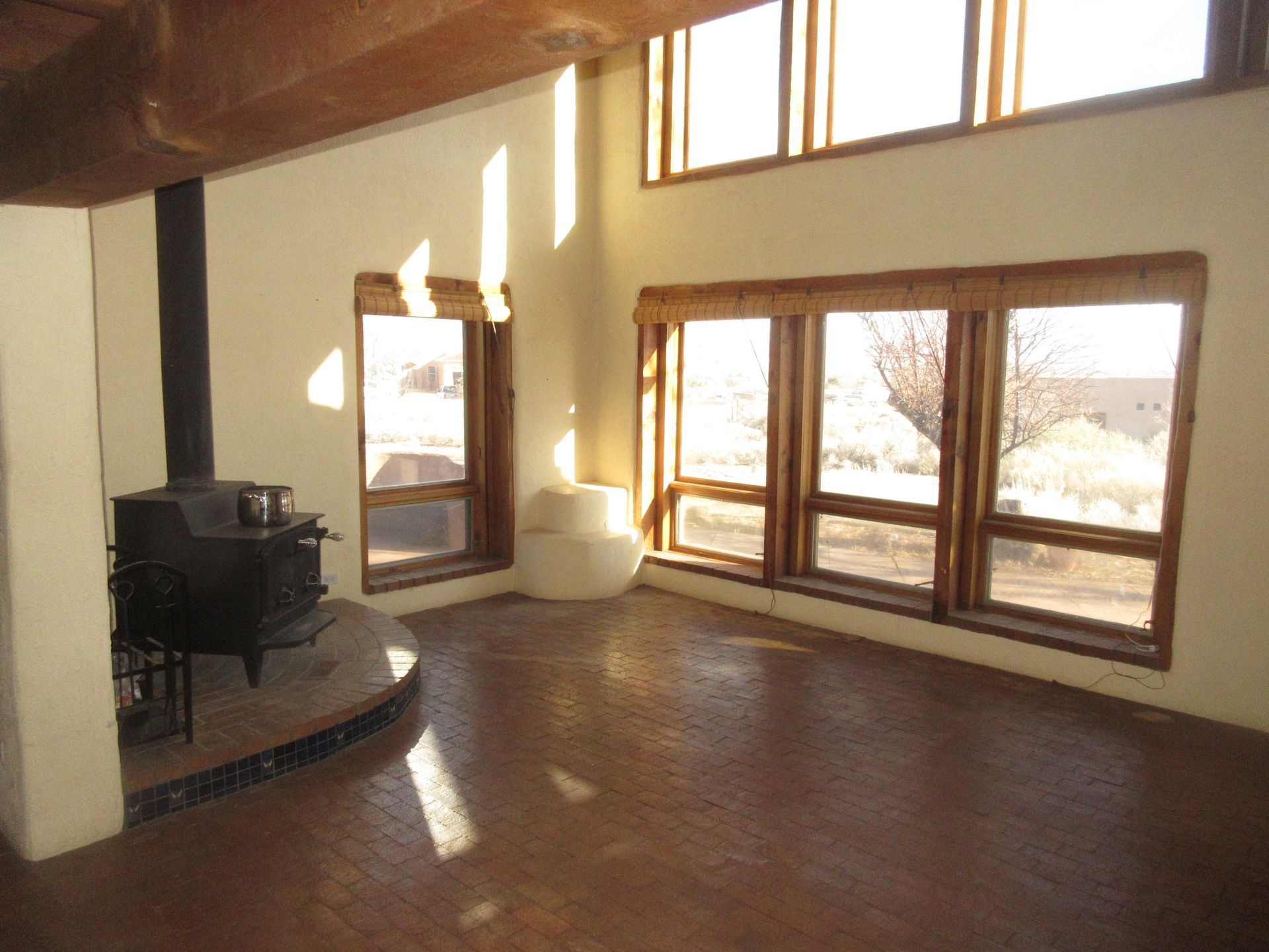A living room with lots of windows and a wood stove
