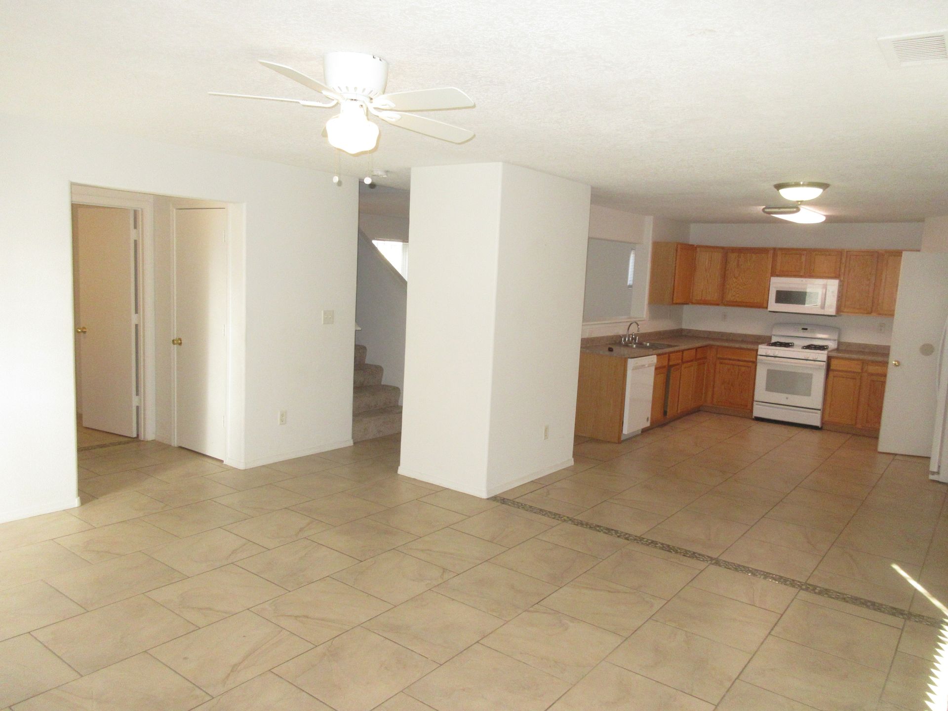 An empty kitchen with wooden cabinets and a ceiling fan