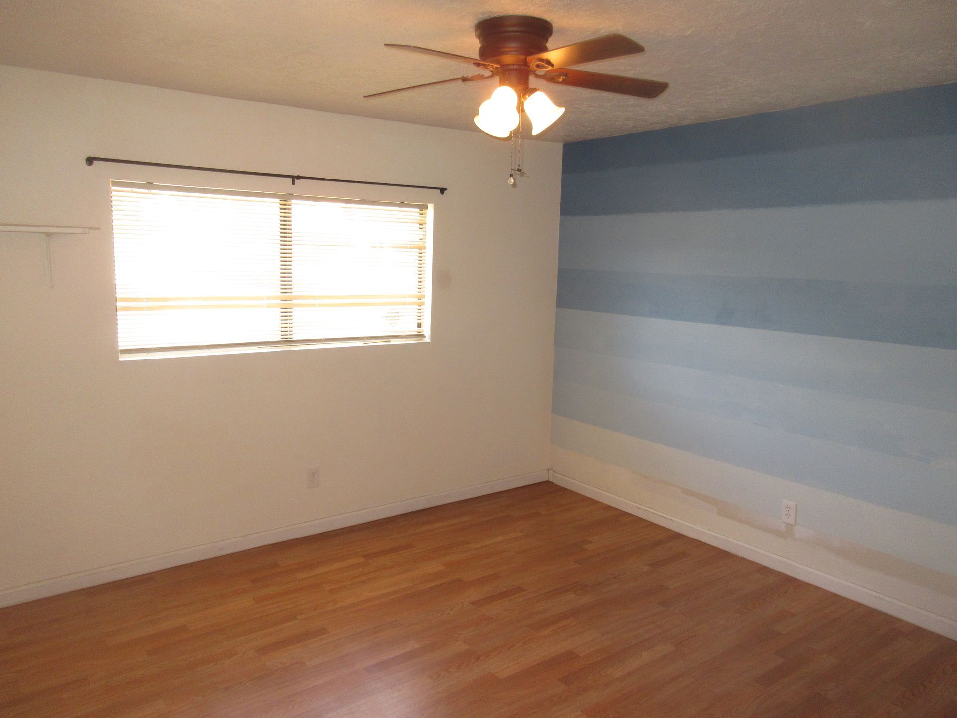 An empty room with a ceiling fan and a window