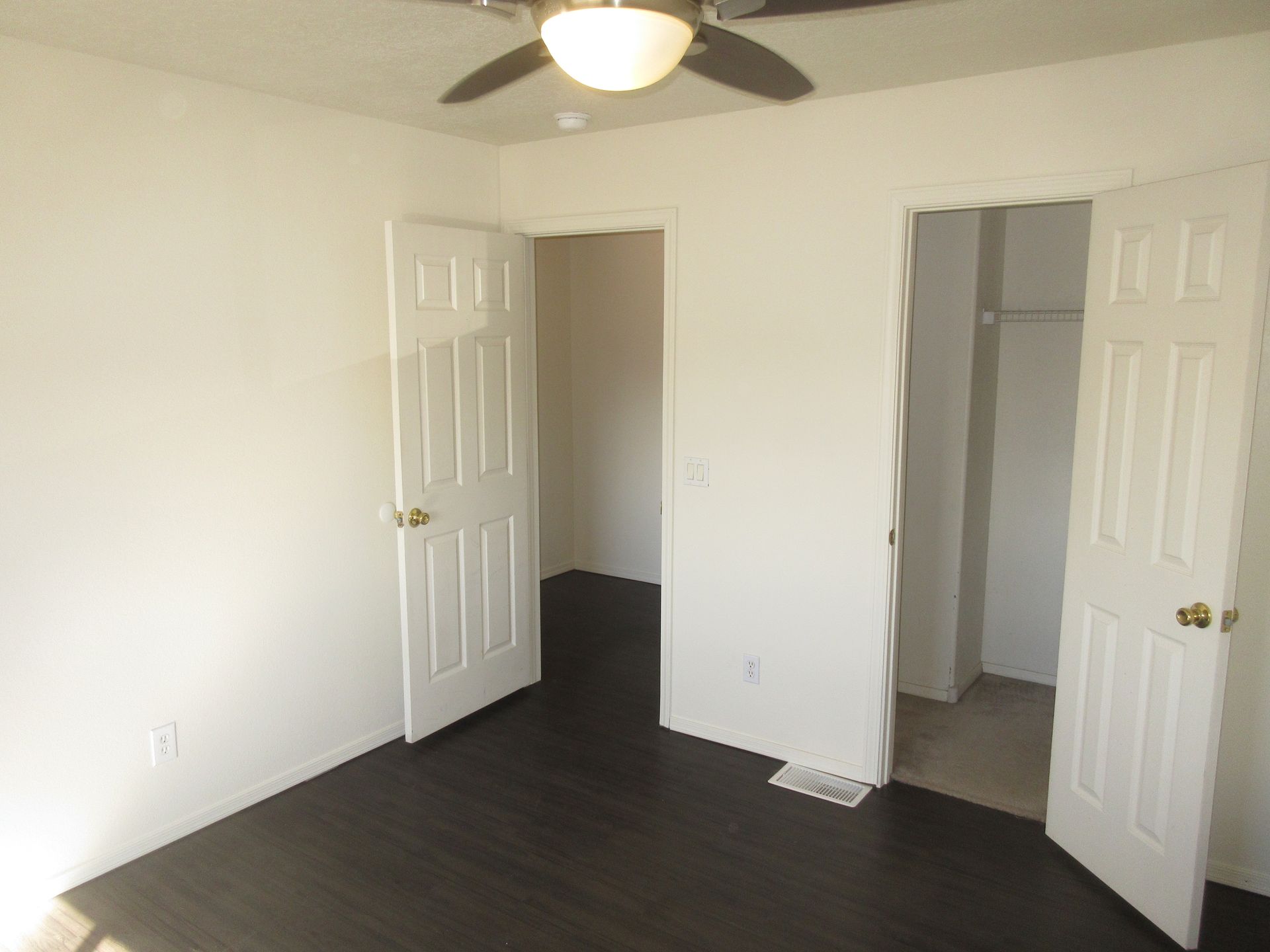 An empty bedroom with a ceiling fan and a closet.