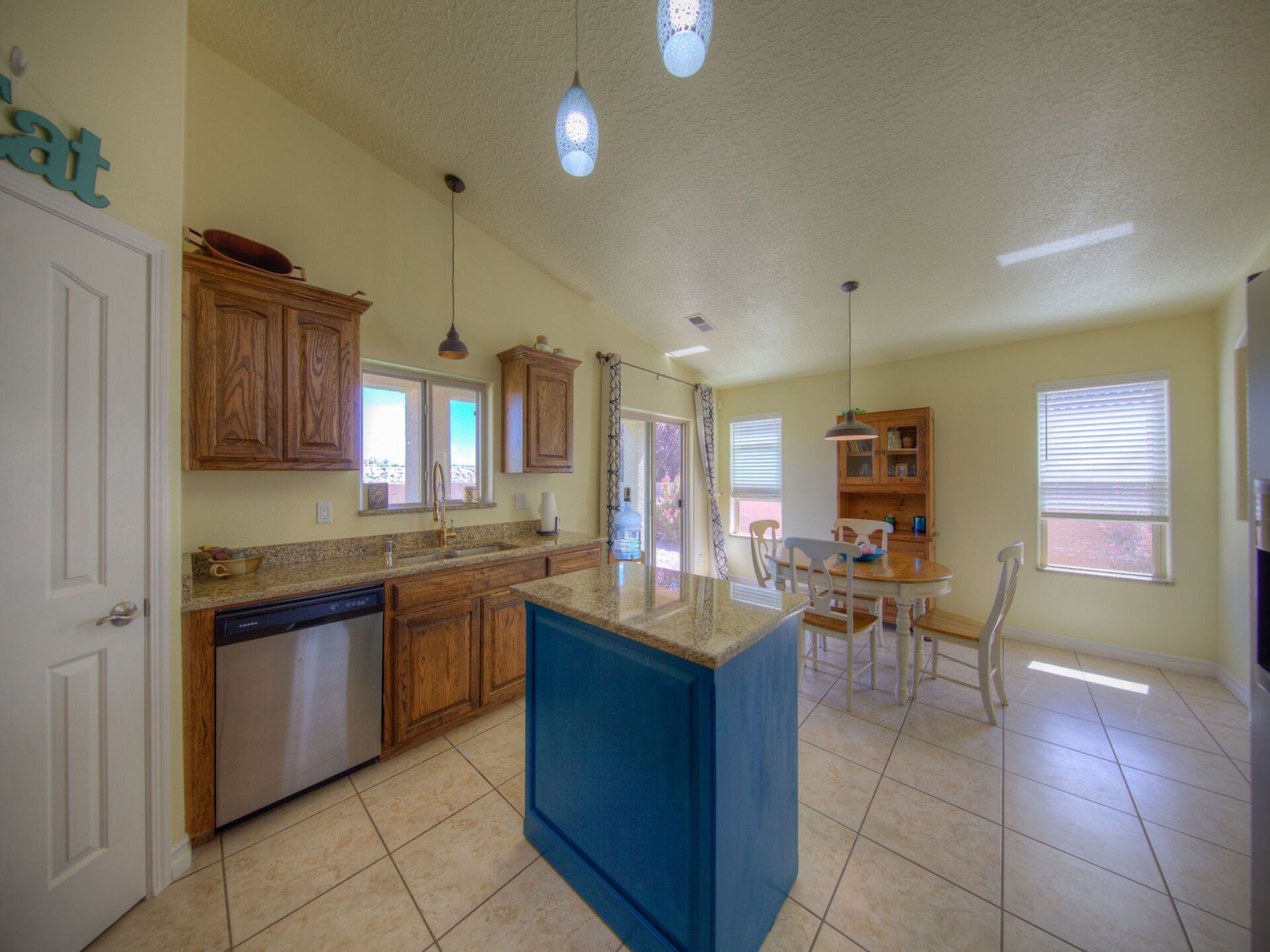 A kitchen with a blue island and a stainless steel dishwasher.