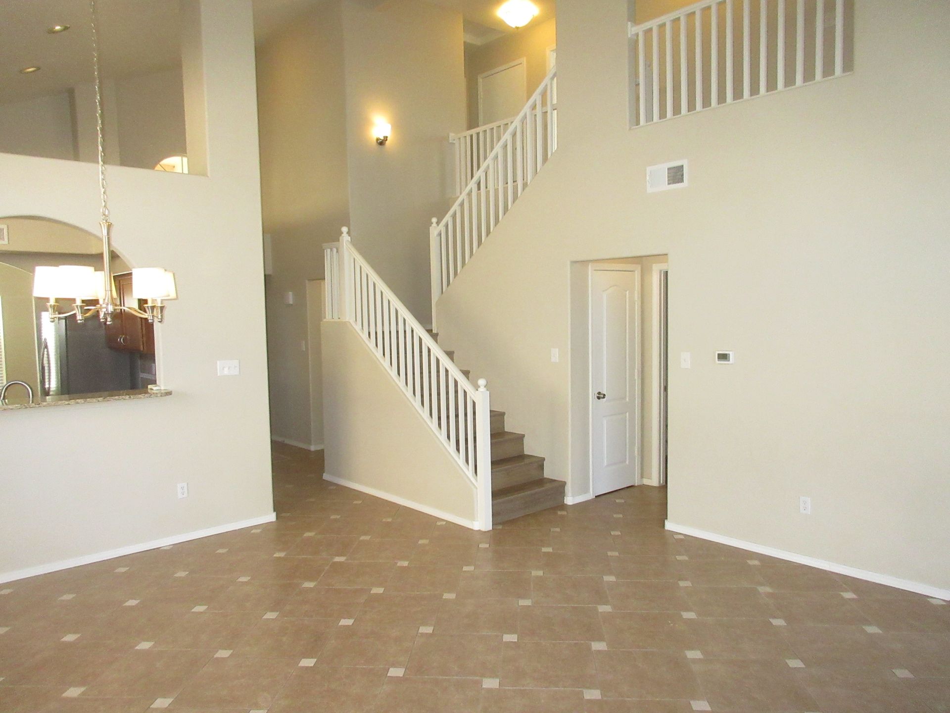 An empty living room with stairs leading up to the second floor