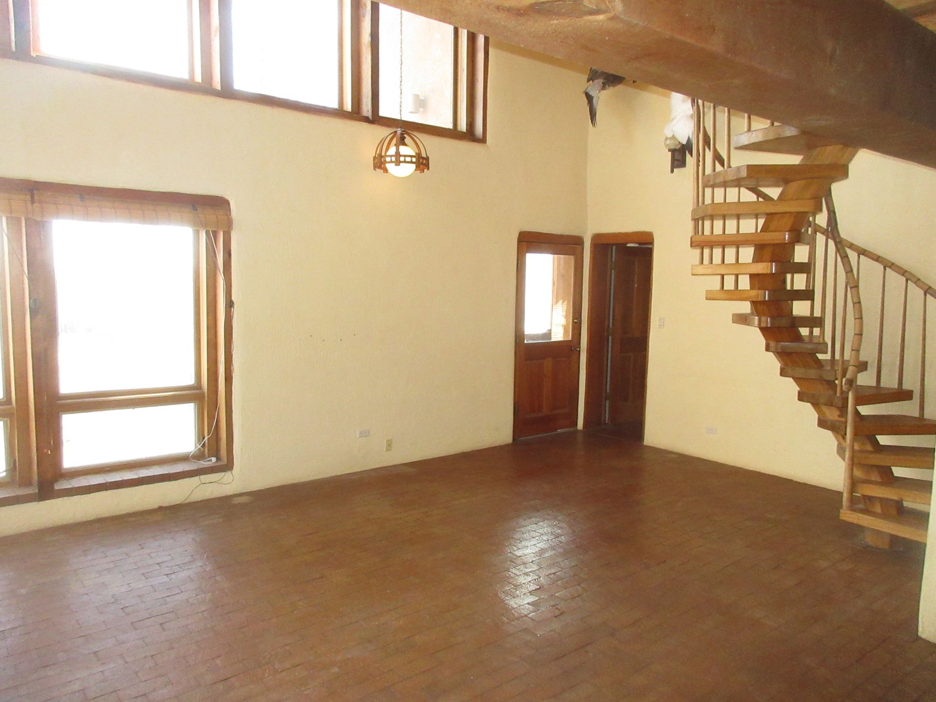 An empty room with a spiral staircase and lots of windows