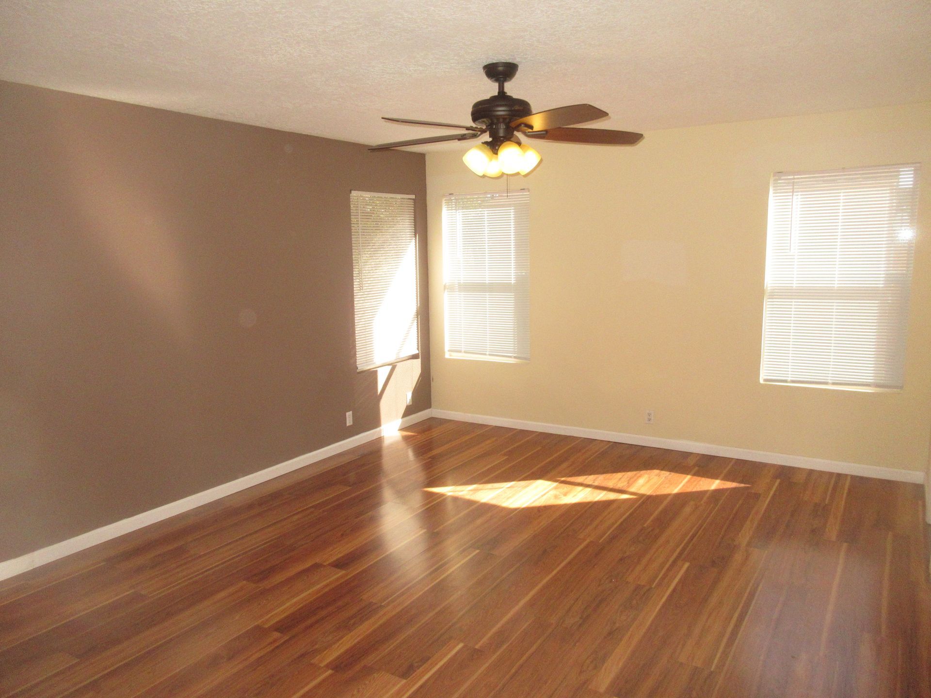 An empty room with hardwood floors and a ceiling fan