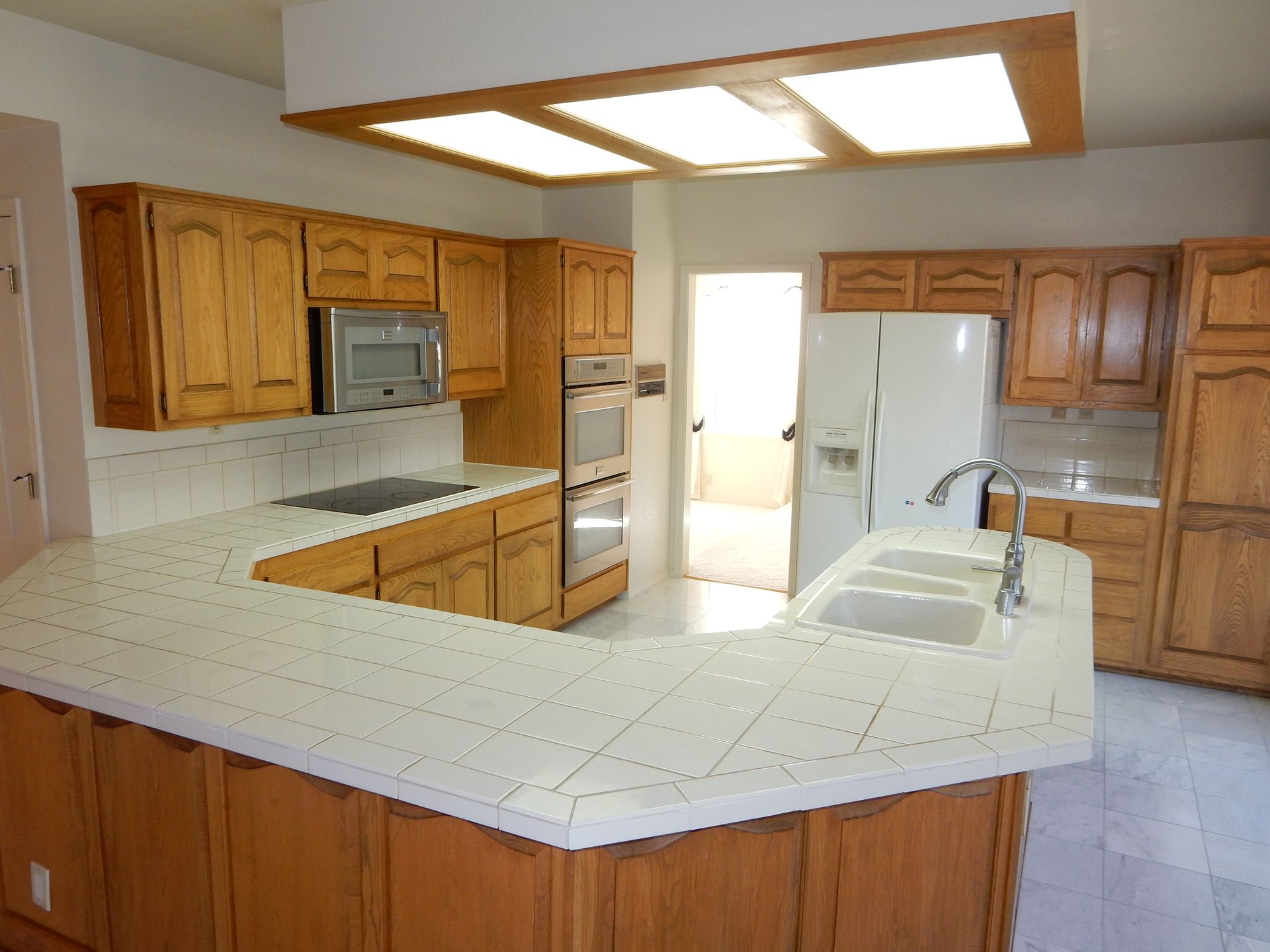 A kitchen with wooden cabinets and white counter tops