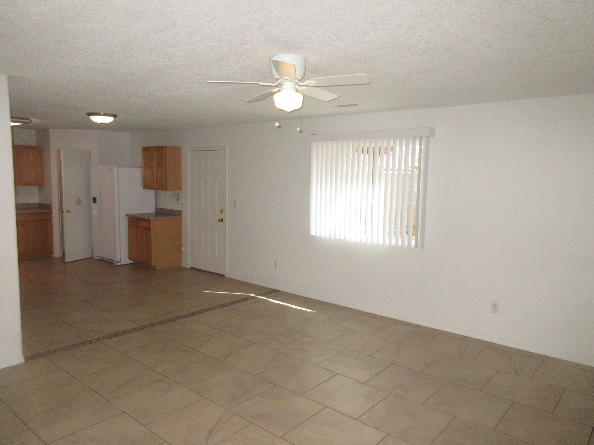 An empty living room with a ceiling fan and a window