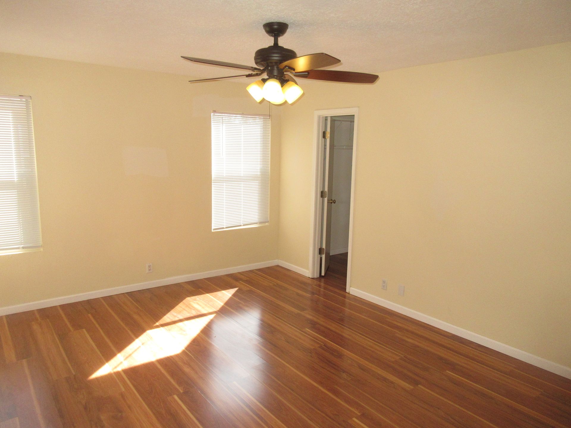 An empty room with hardwood floors and a ceiling fan
