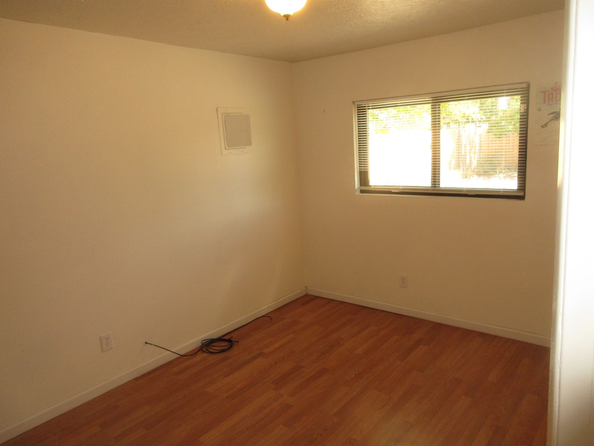An empty room with hardwood floors and a window.