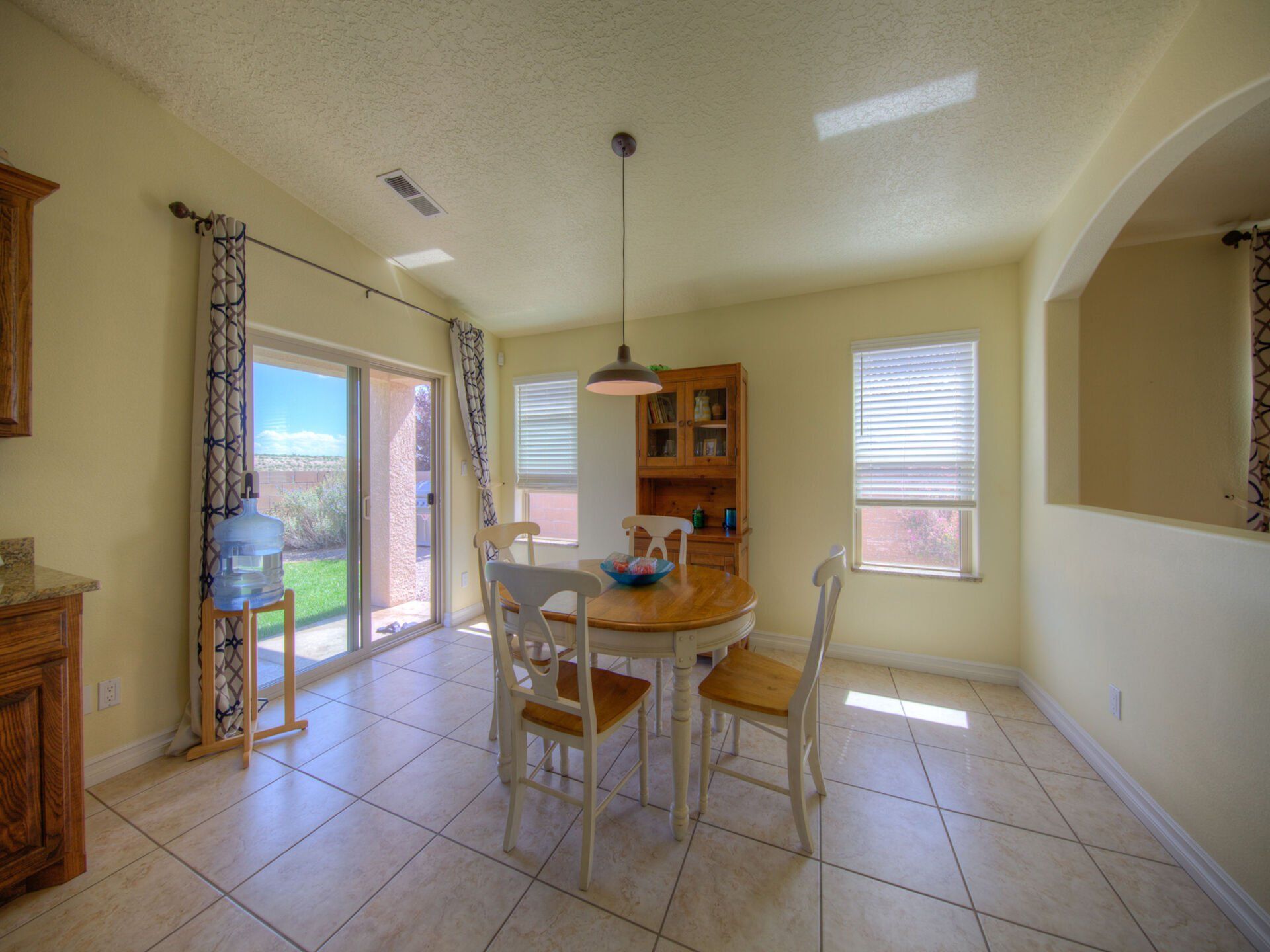 A dining room with a table and chairs and a sliding glass door.