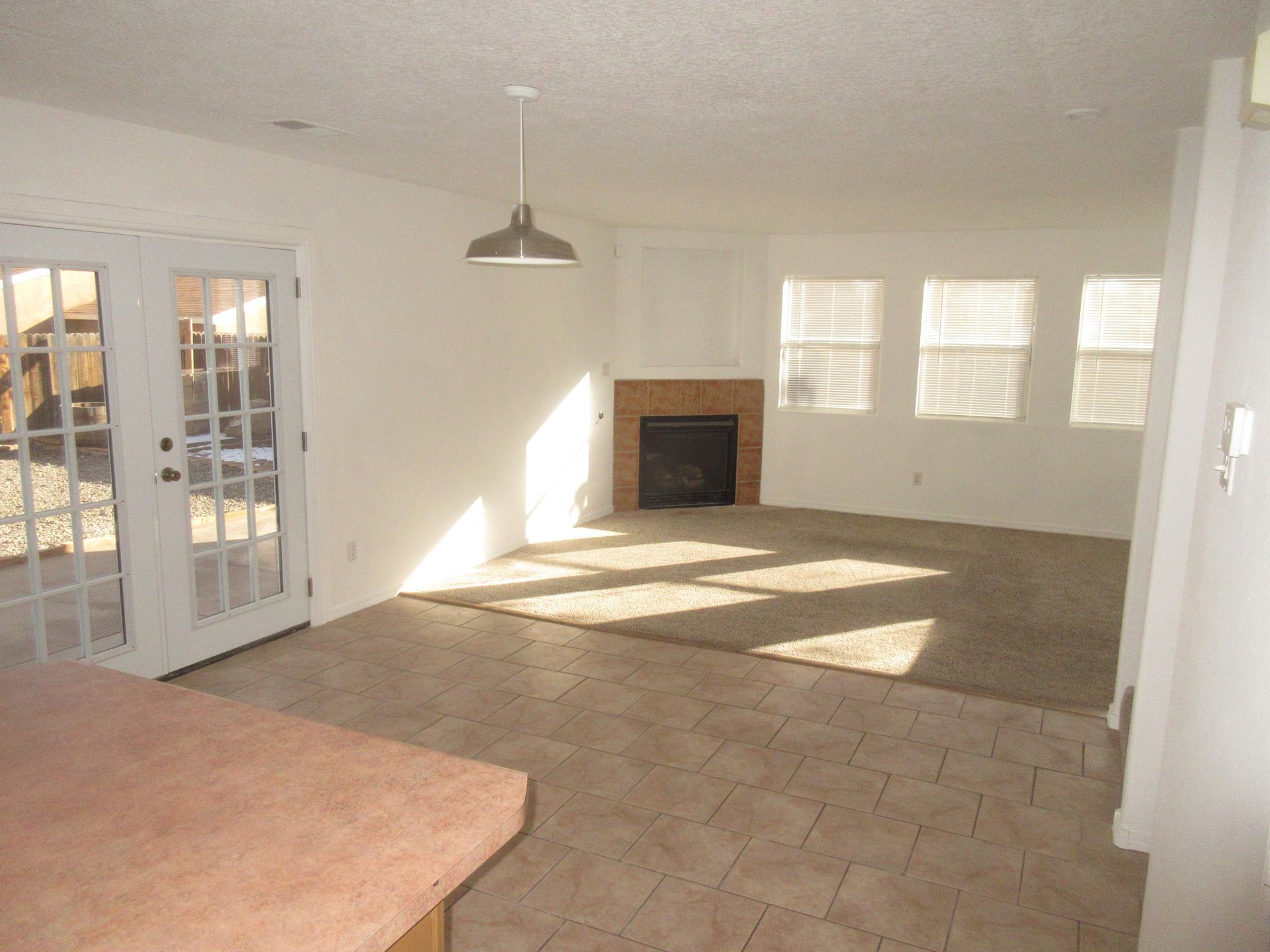An empty living room with a fireplace and french doors