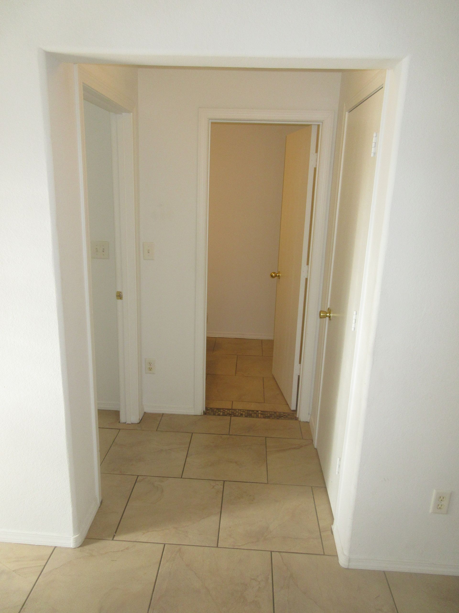 An empty hallway with a tiled floor and a white door