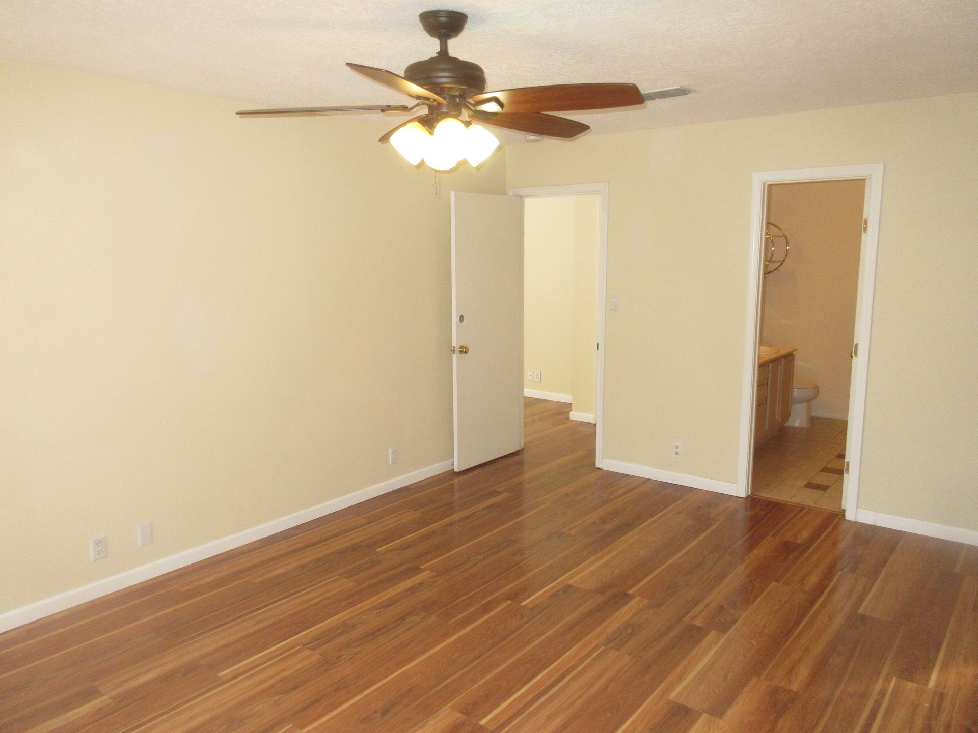 An empty room with hardwood floors and a ceiling fan