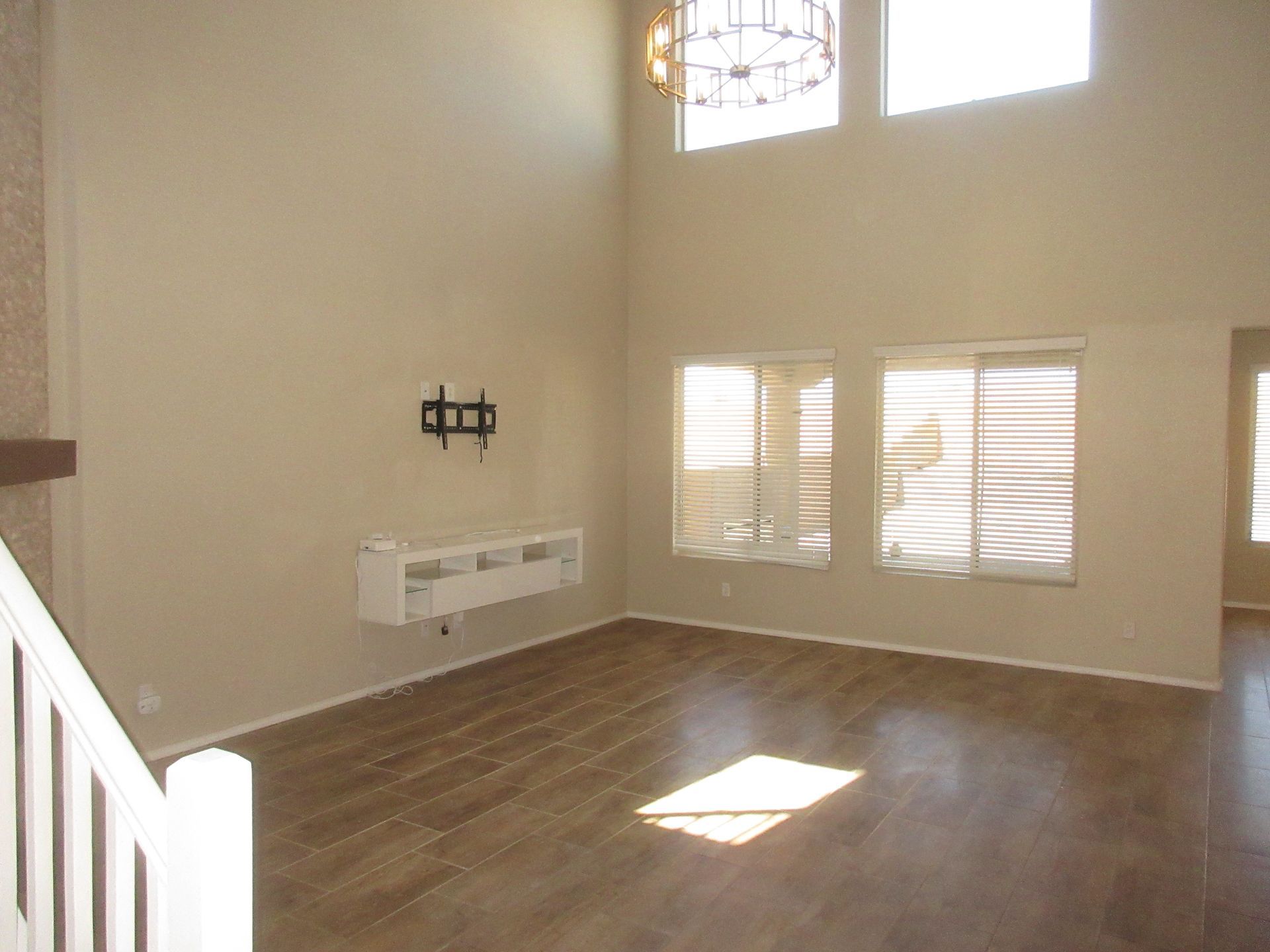An empty living room with hardwood floors and a flat screen tv mounted on the wall.