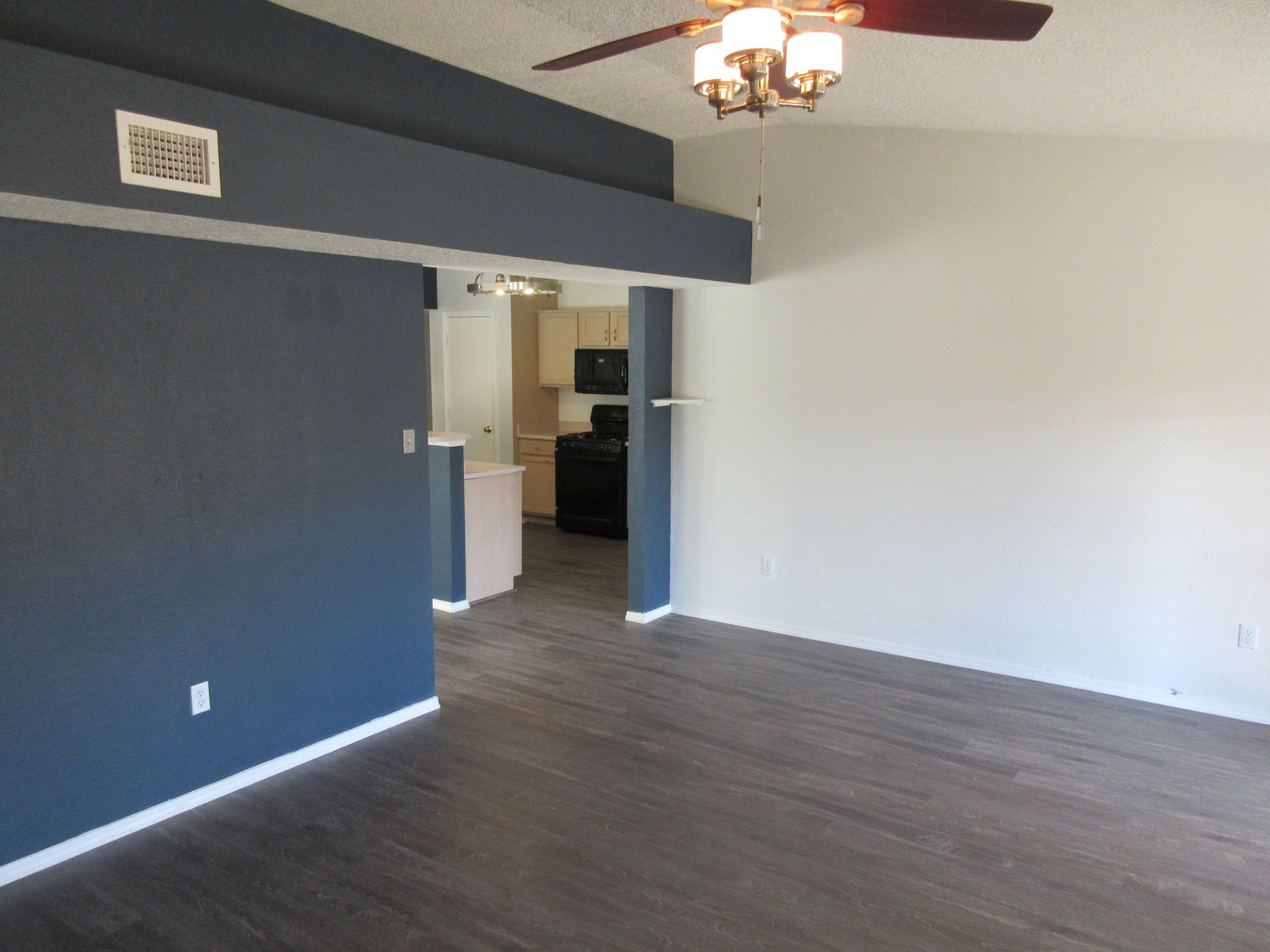An empty living room with a ceiling fan and a chandelier