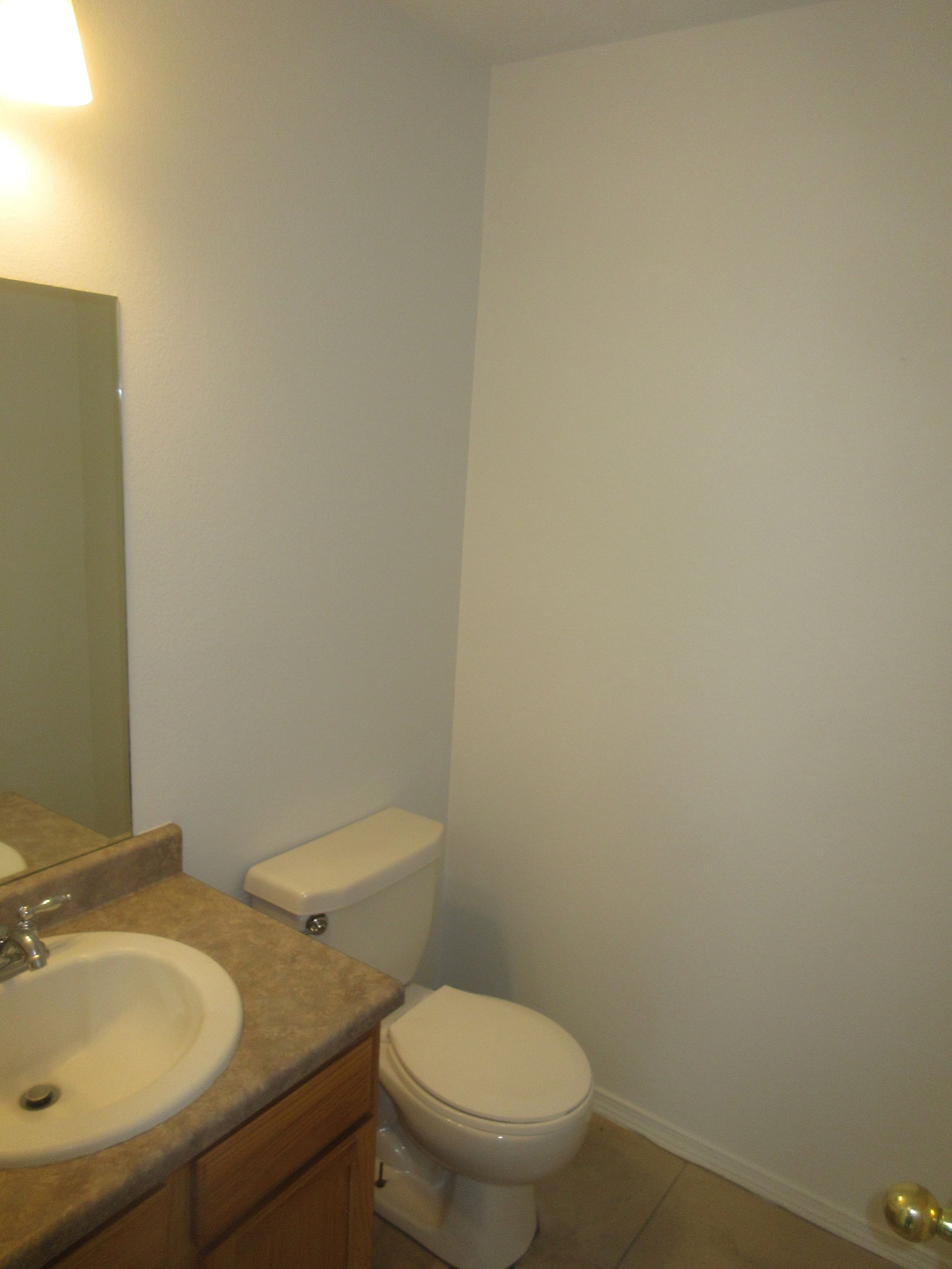 A bathroom with a toilet , sink and mirror