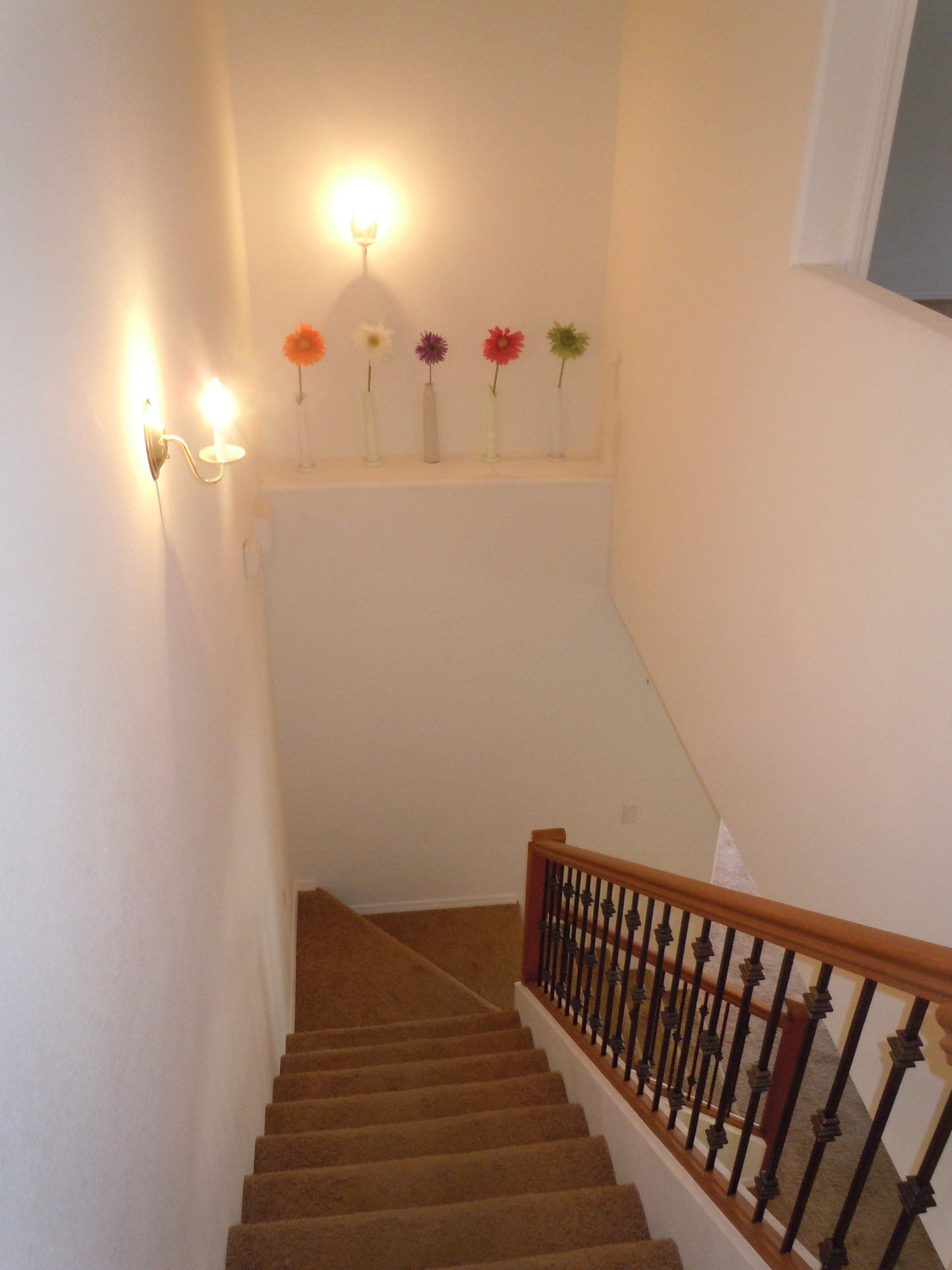 A staircase with a railing and flowers on the wall