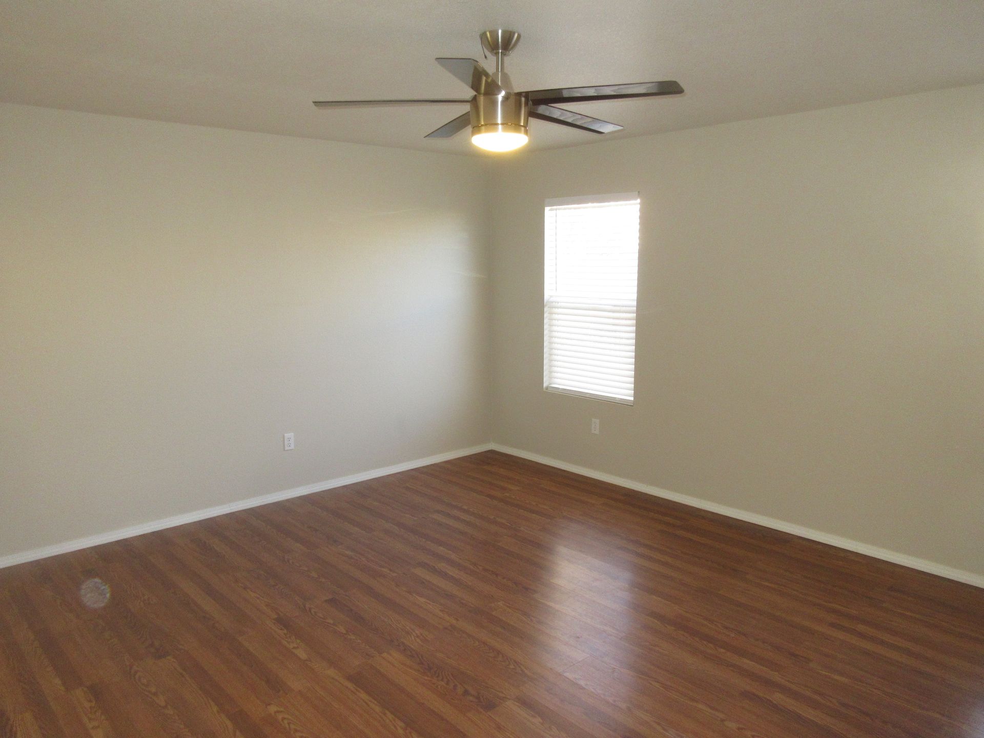An empty room with hardwood floors and a ceiling fan
