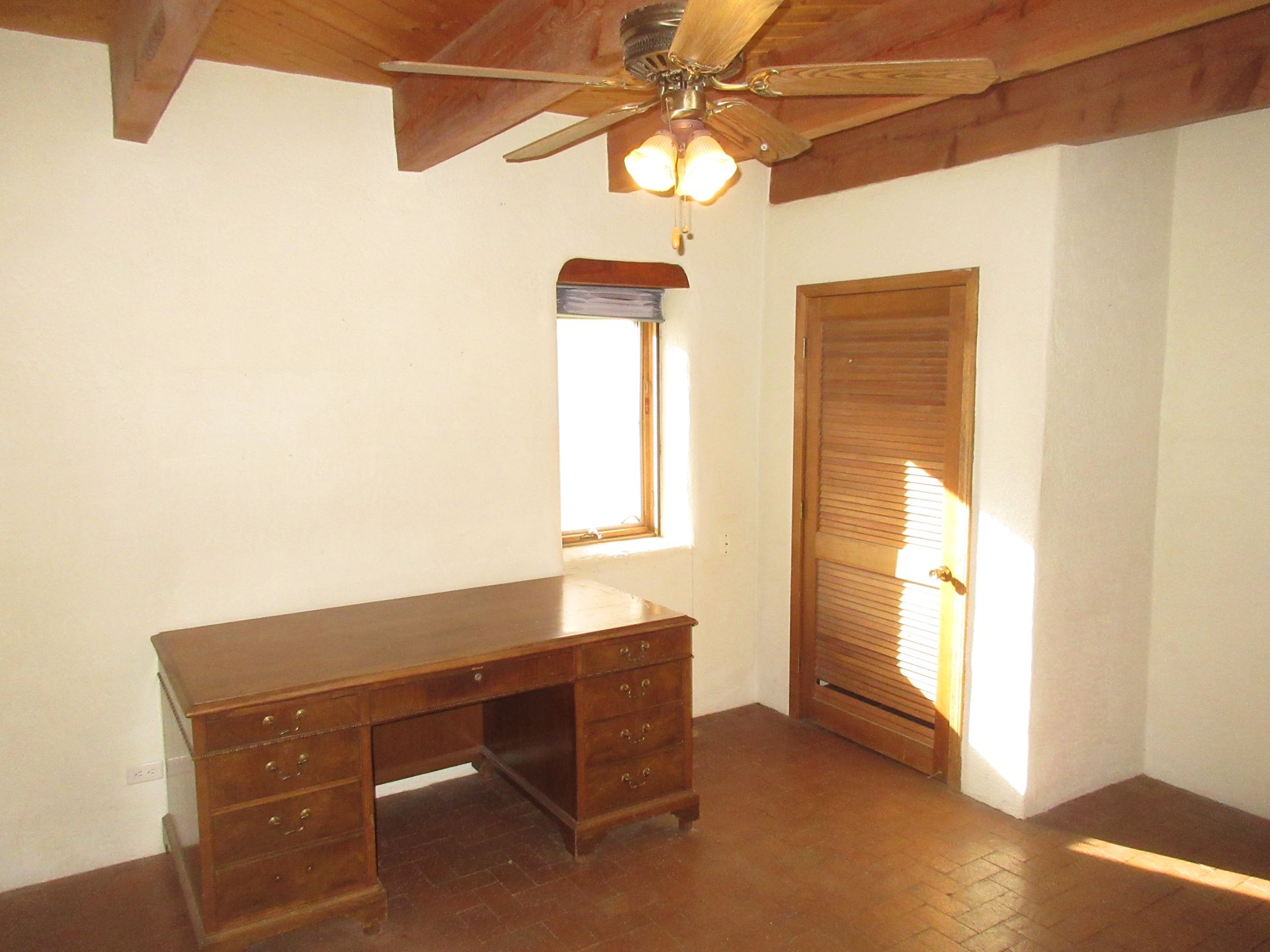 An empty room with a desk and a ceiling fan