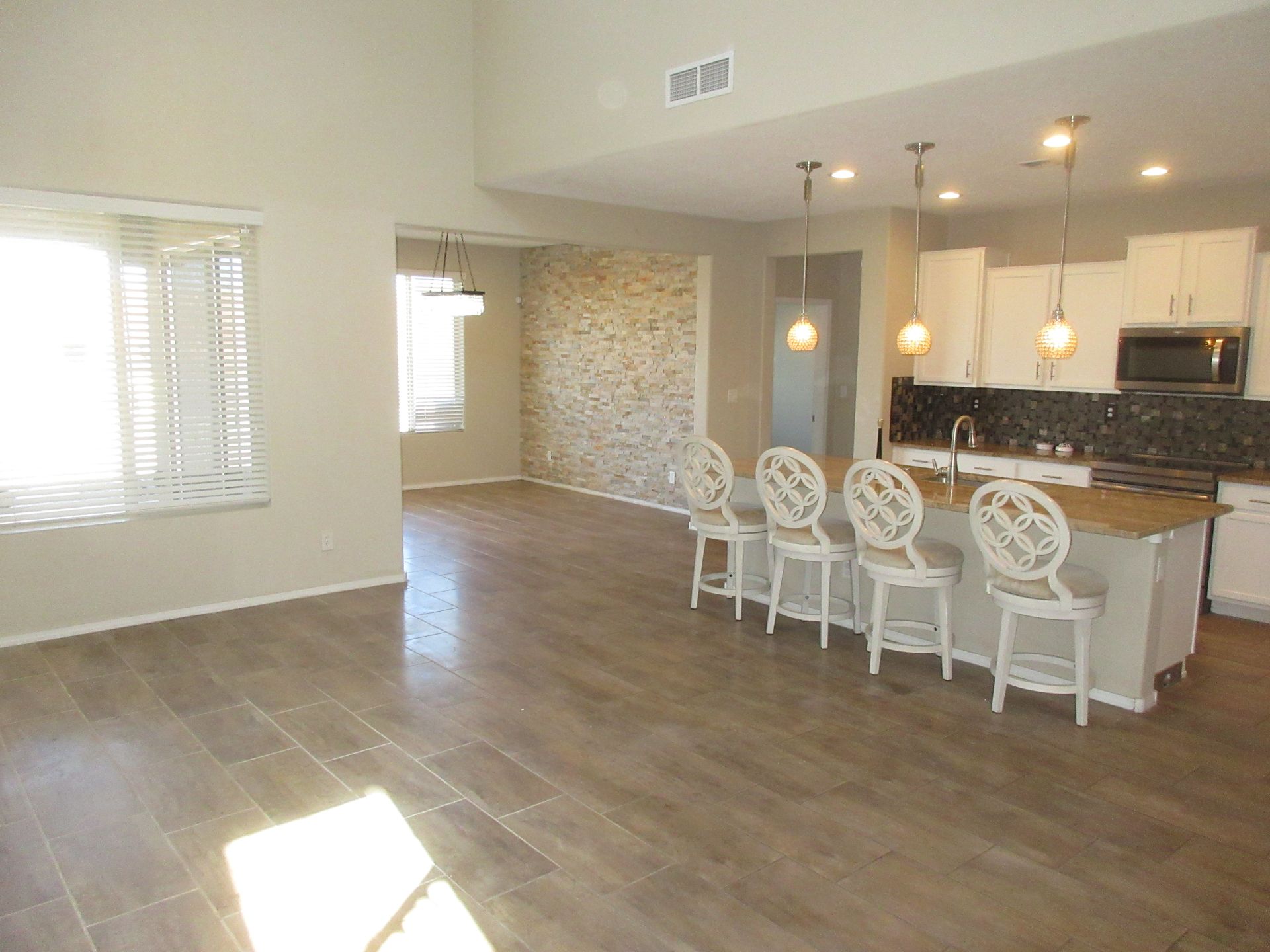 A large empty living room with a kitchen in the background.