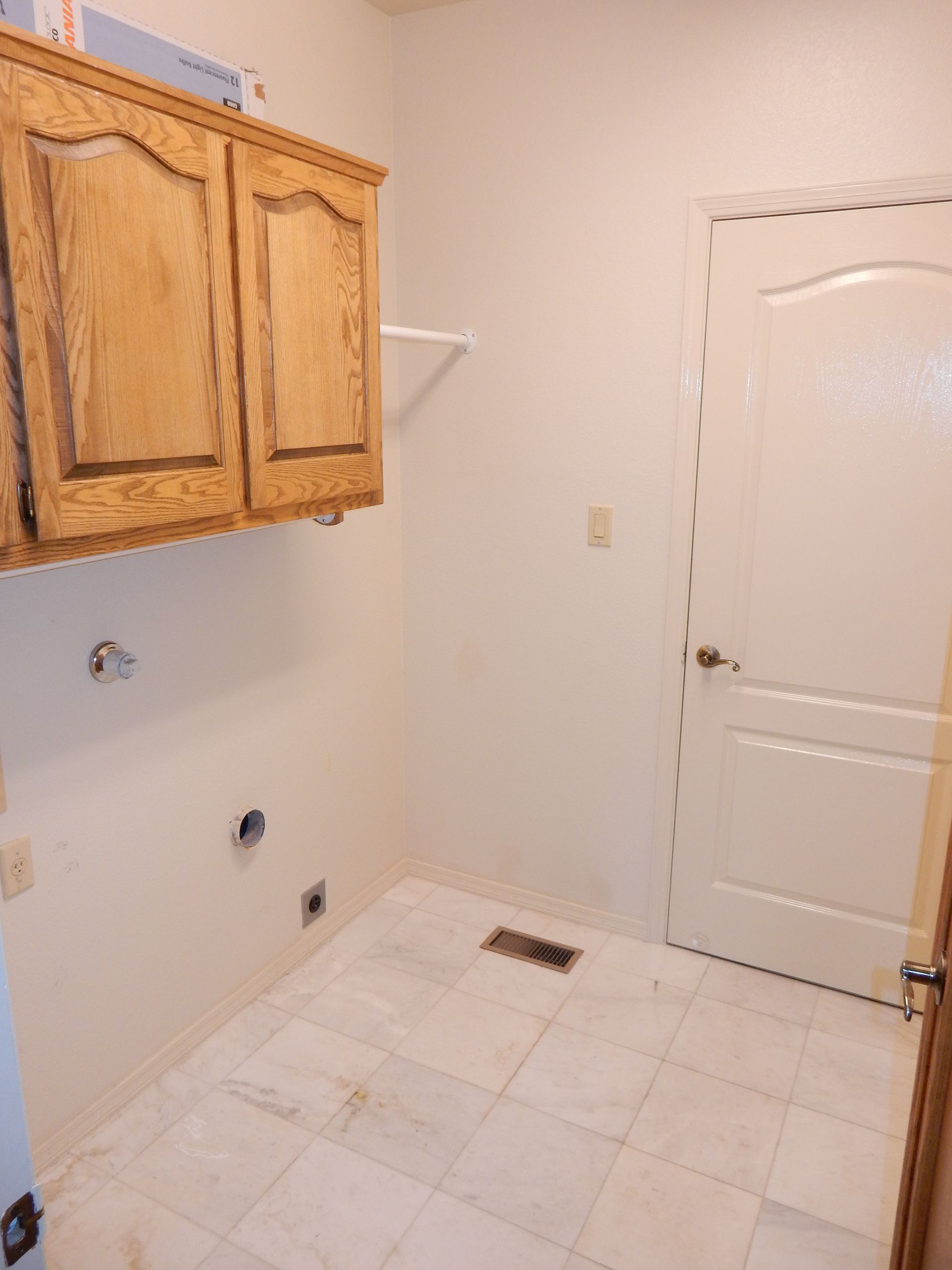 A laundry room with wooden cabinets and a white door.