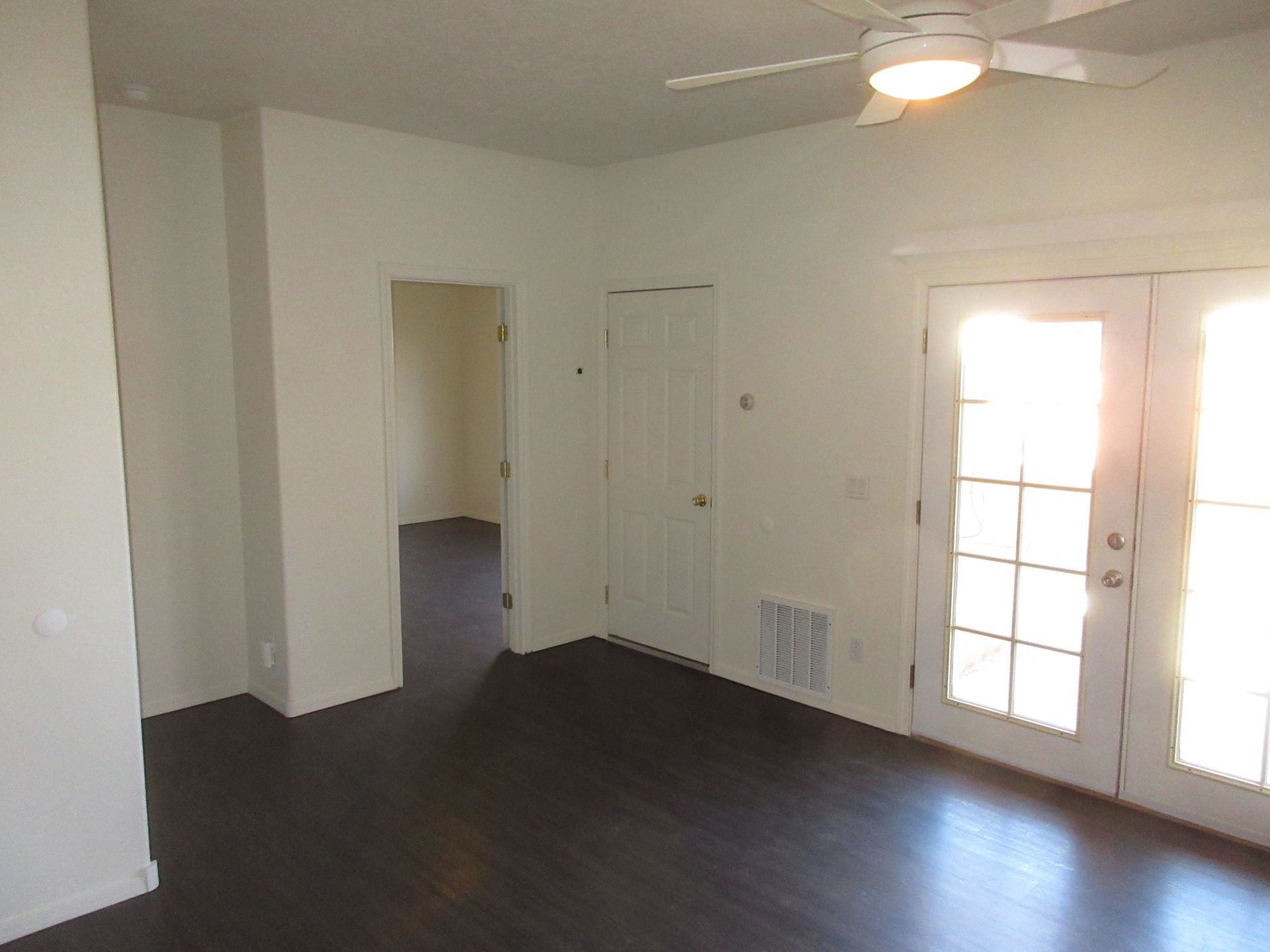 An empty room with a ceiling fan and french doors