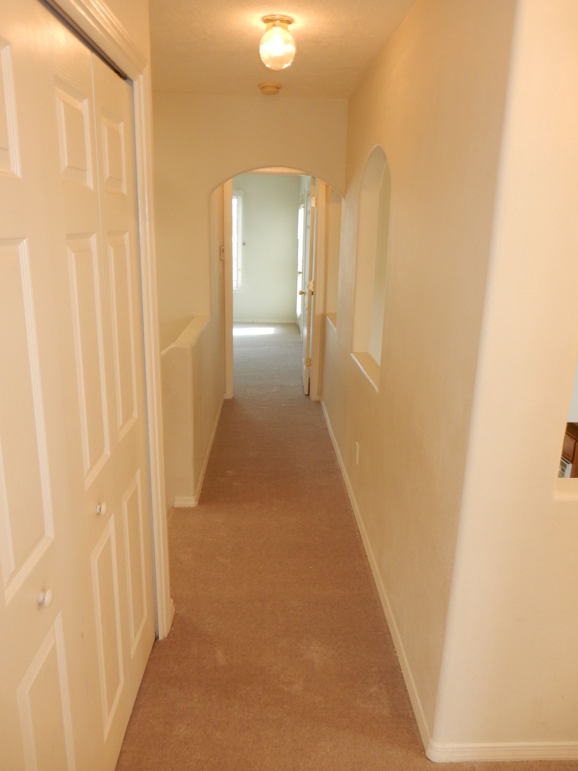 A long hallway with white walls and brown carpet