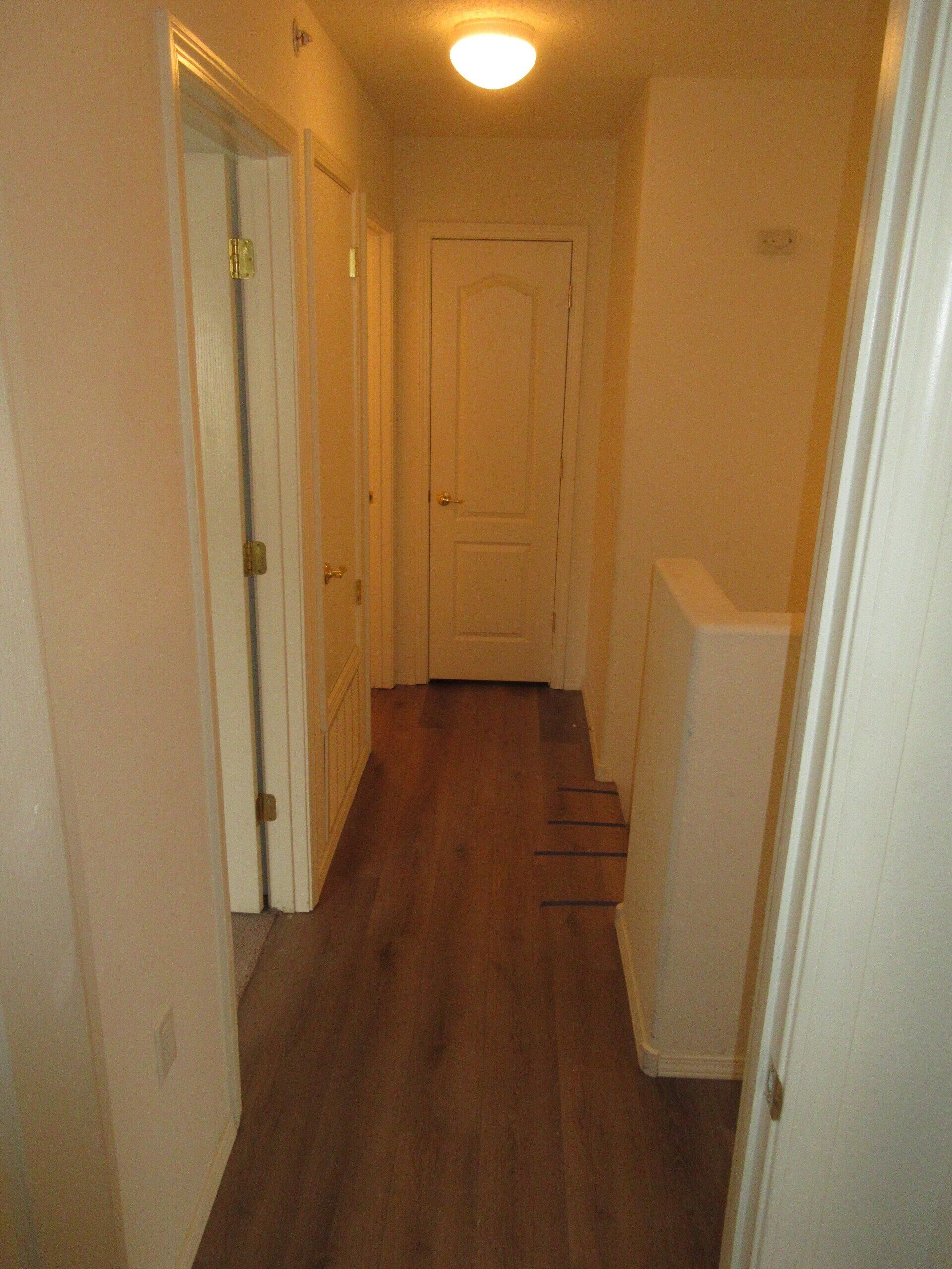 A hallway with hardwood floors and white doors