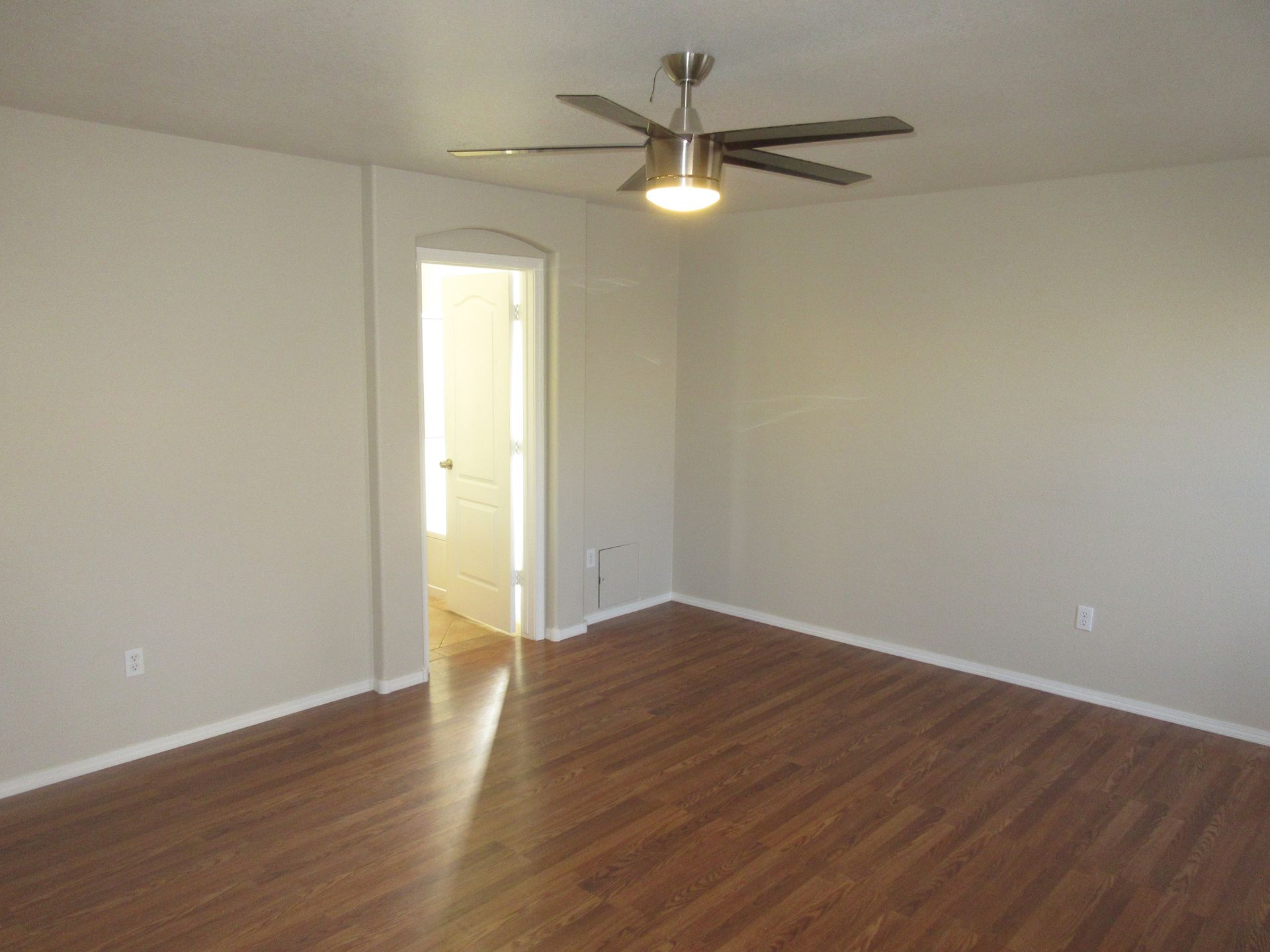 An empty living room with hardwood floors and a ceiling fan.