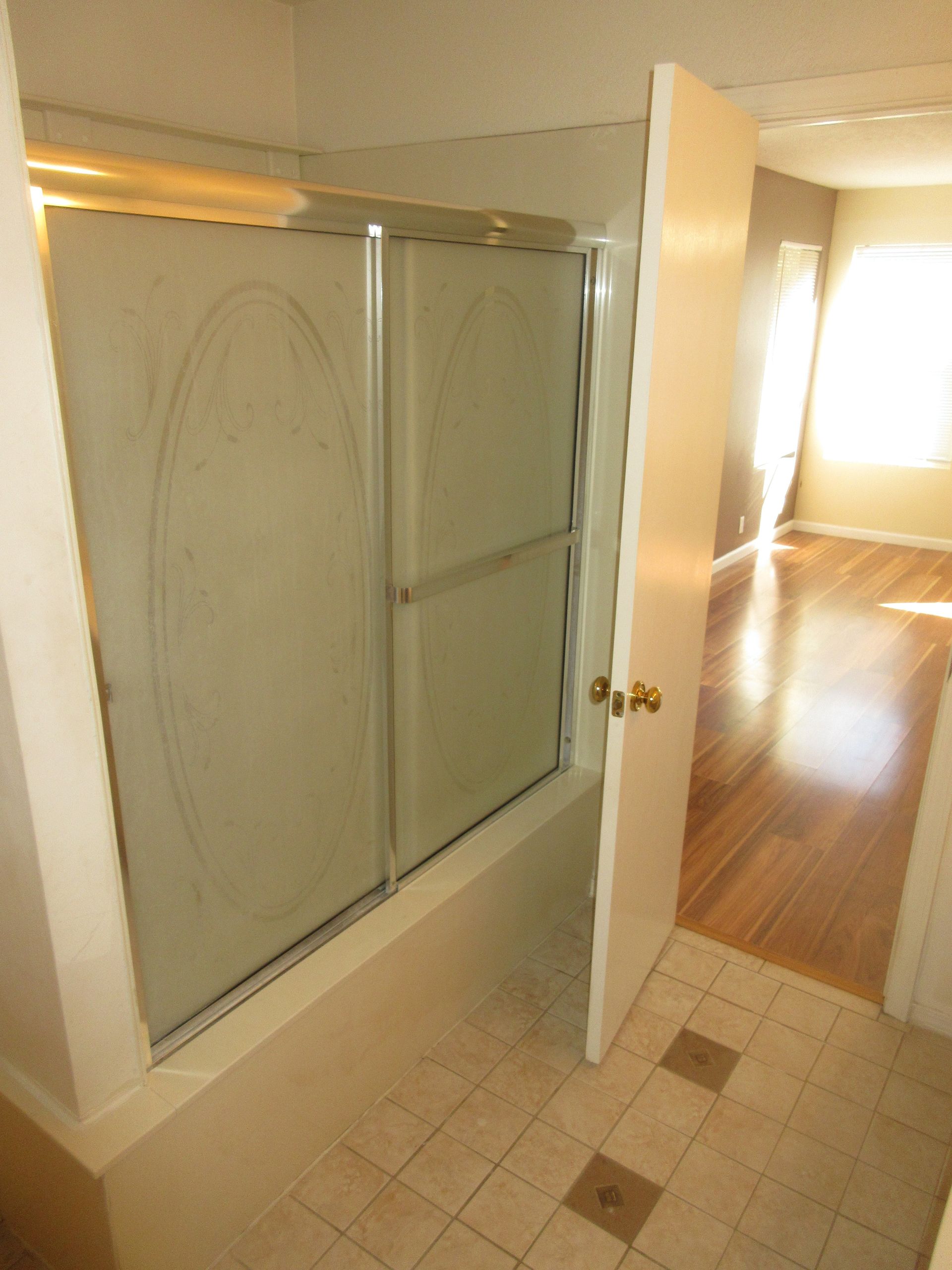 A bathroom with a sliding glass shower door