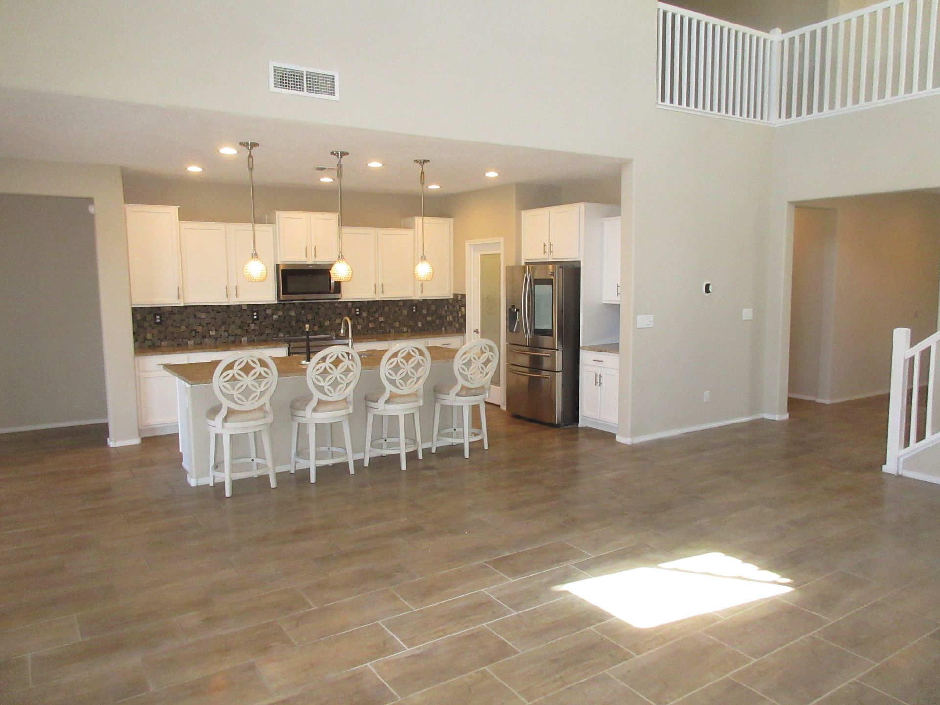A kitchen with white cabinets and a stainless steel refrigerator