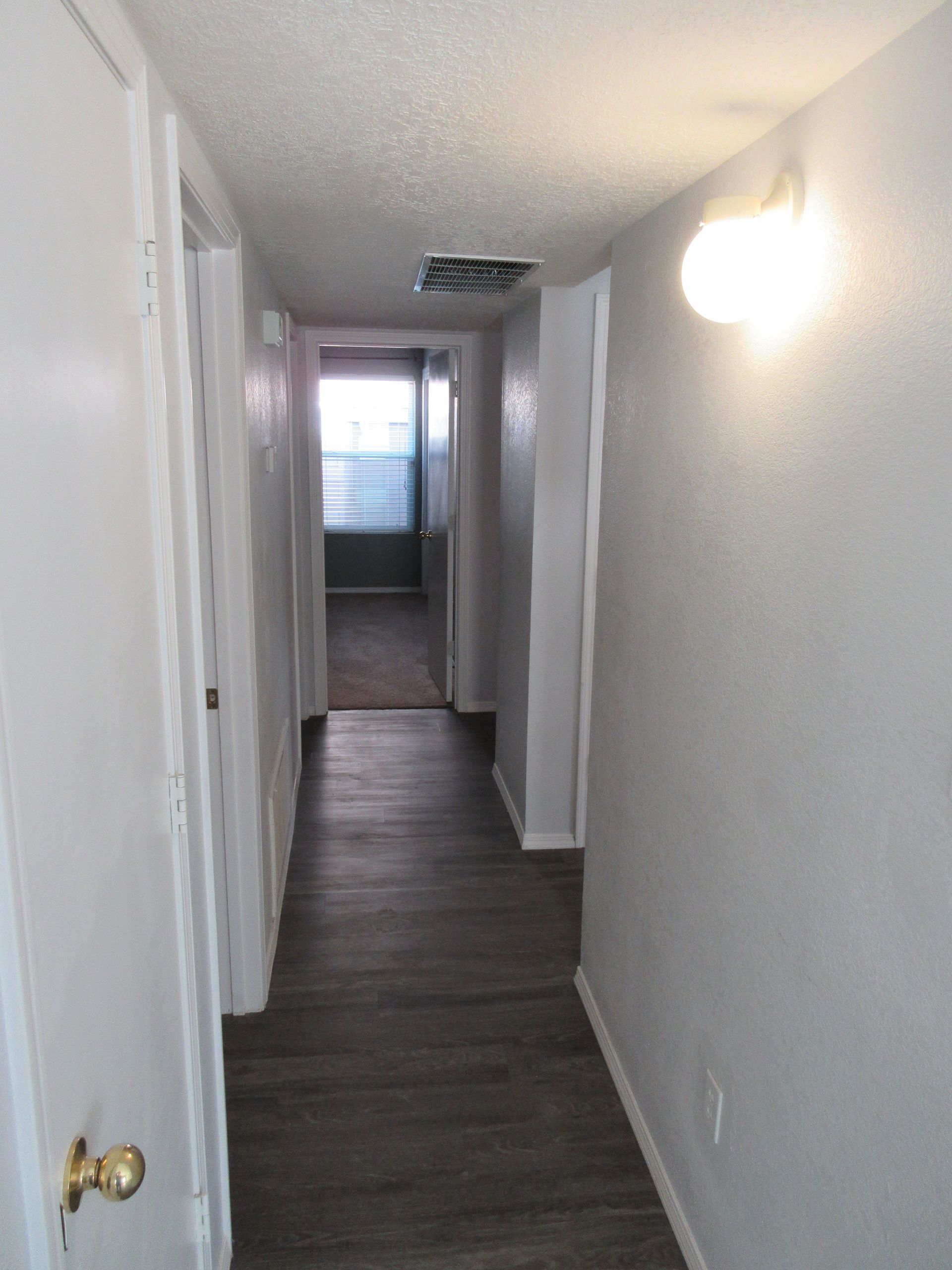 A long hallway in a house with wooden floors and white walls.