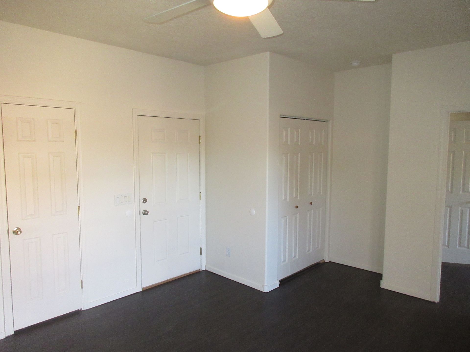An empty bedroom with a ceiling fan and closets