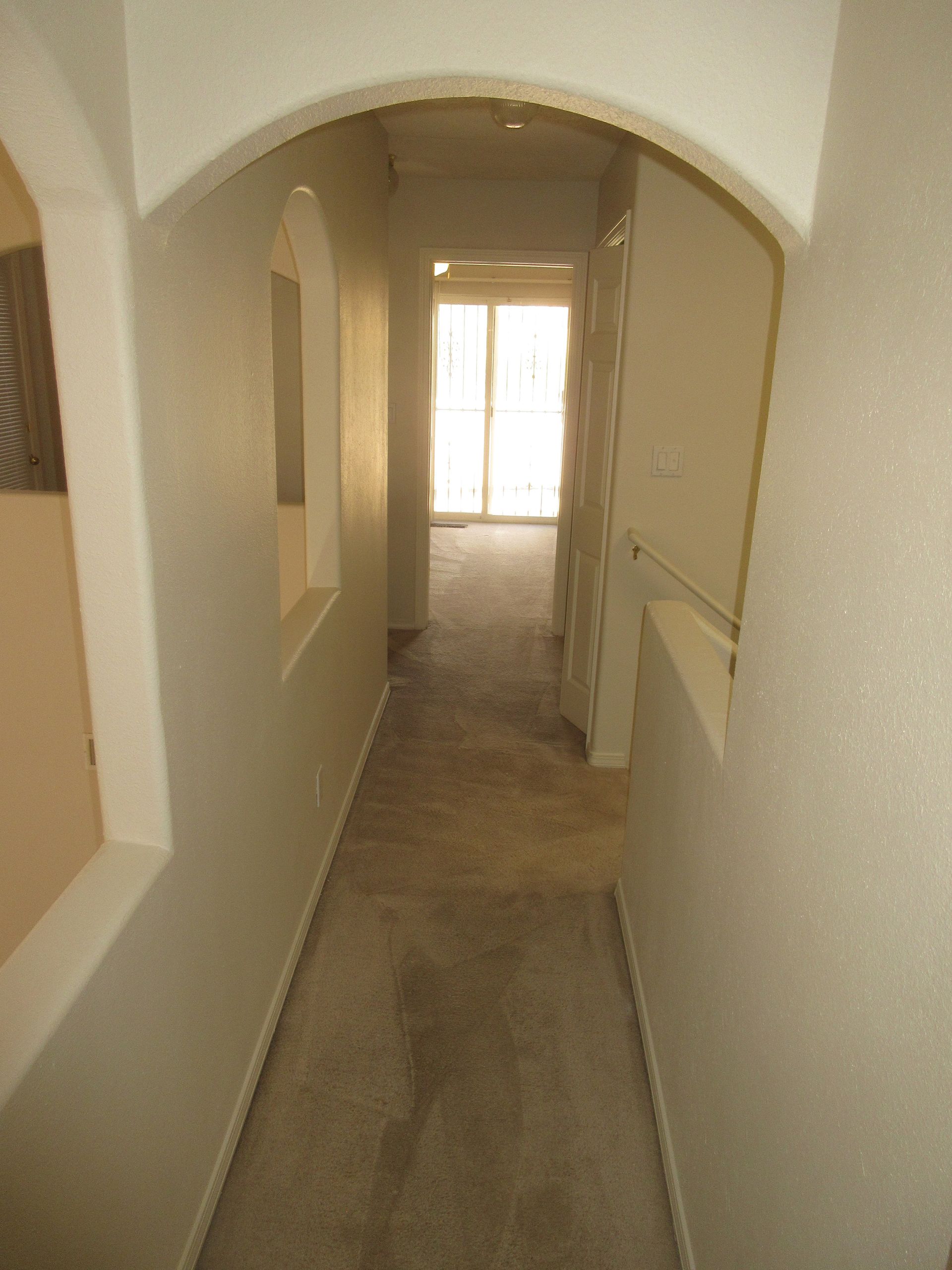 A long hallway with arches and a sliding glass door