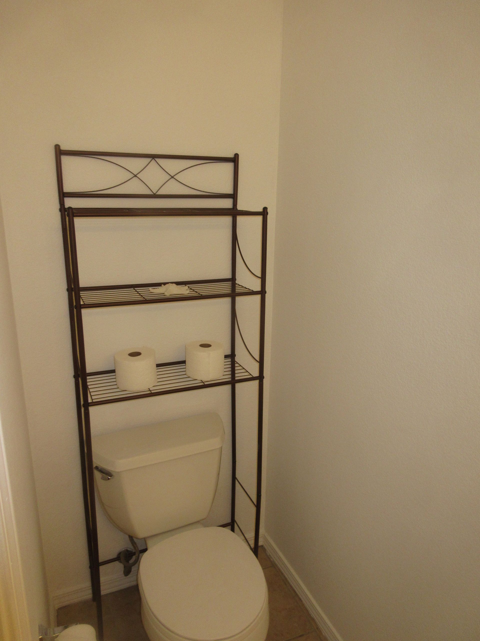 A bathroom with a toilet and a shelf with toilet paper on it