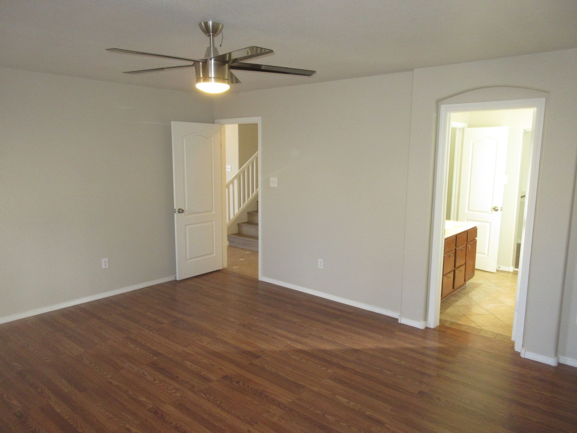 A living room with hardwood floors and a ceiling fan.