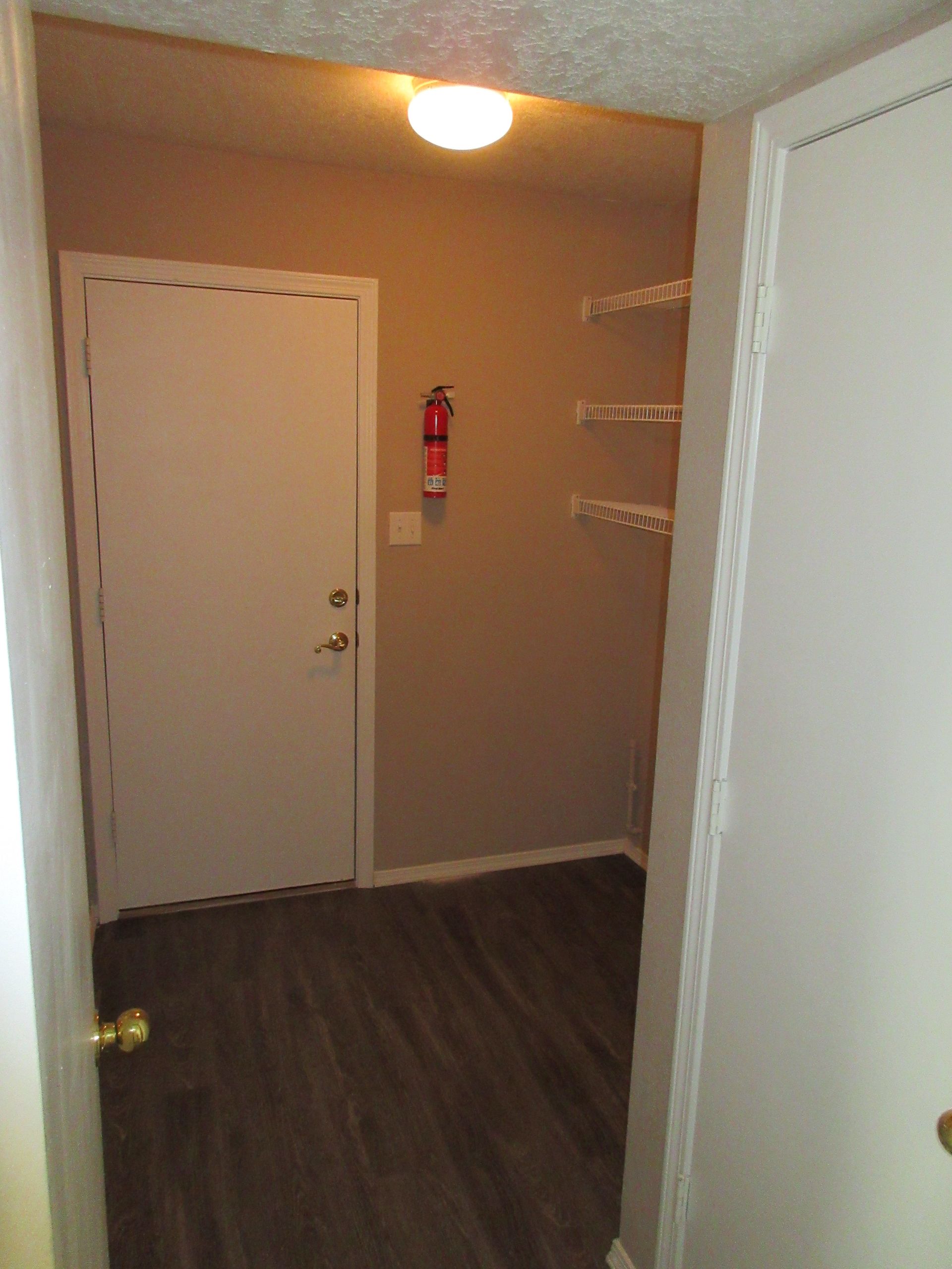 A hallway with a door and a fire extinguisher on the wall.