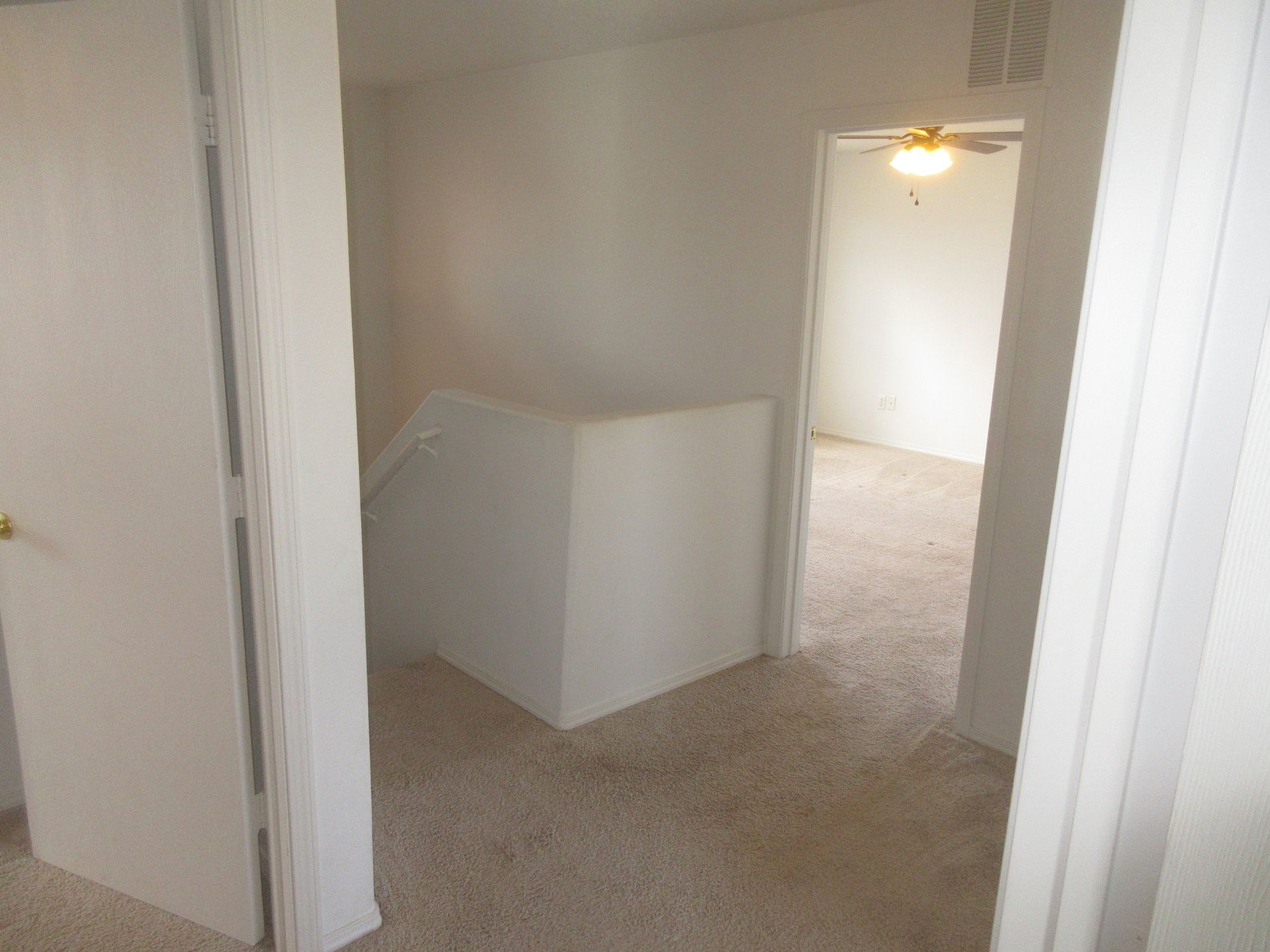 A hallway with a staircase and a ceiling fan